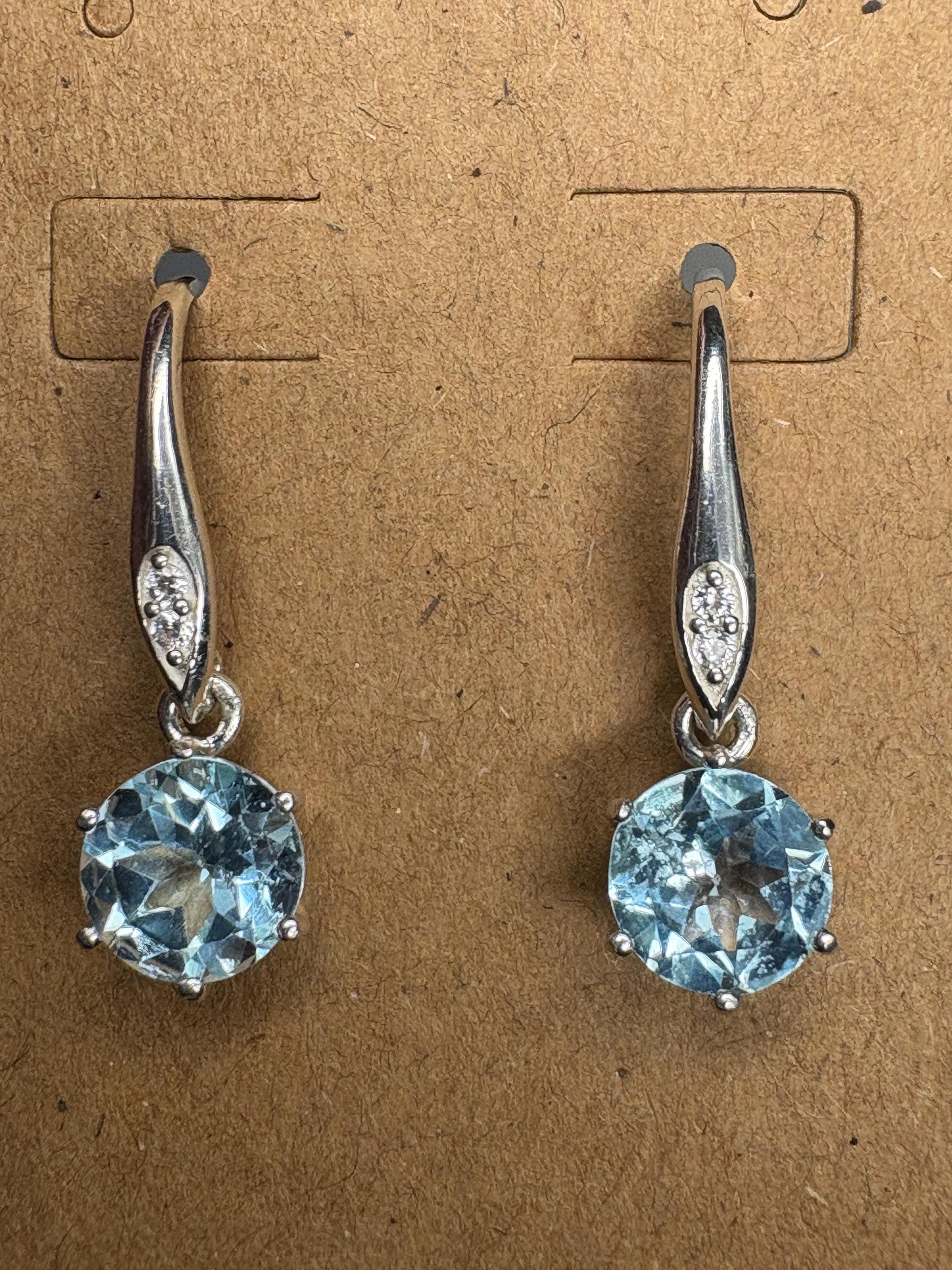 Sterling silver dangle earrings with round blue topaz and white zircon accents.