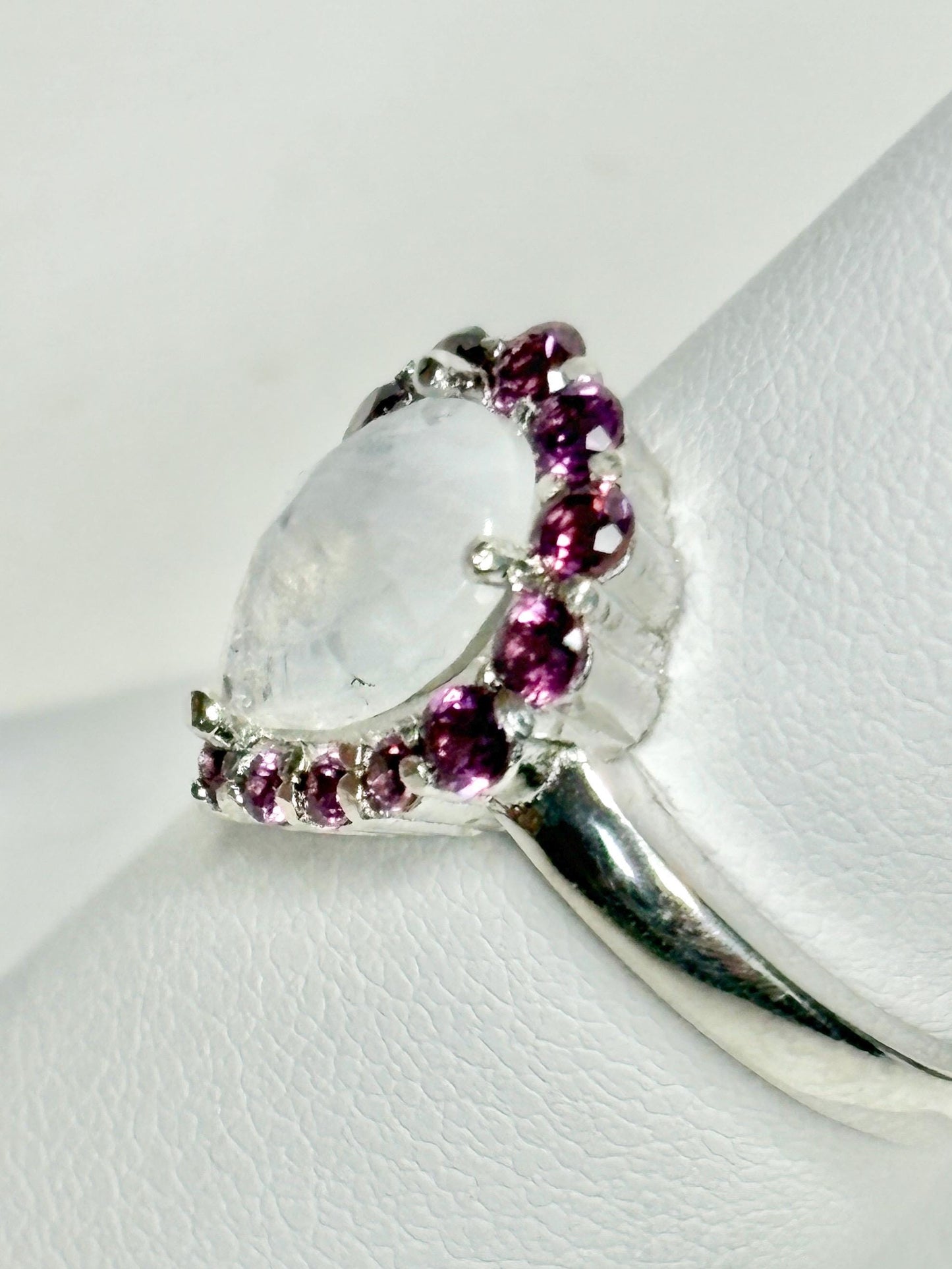 Sterling silver ring with a pear-shaped rainbow moonstone and a halo of rhodolite garnets.