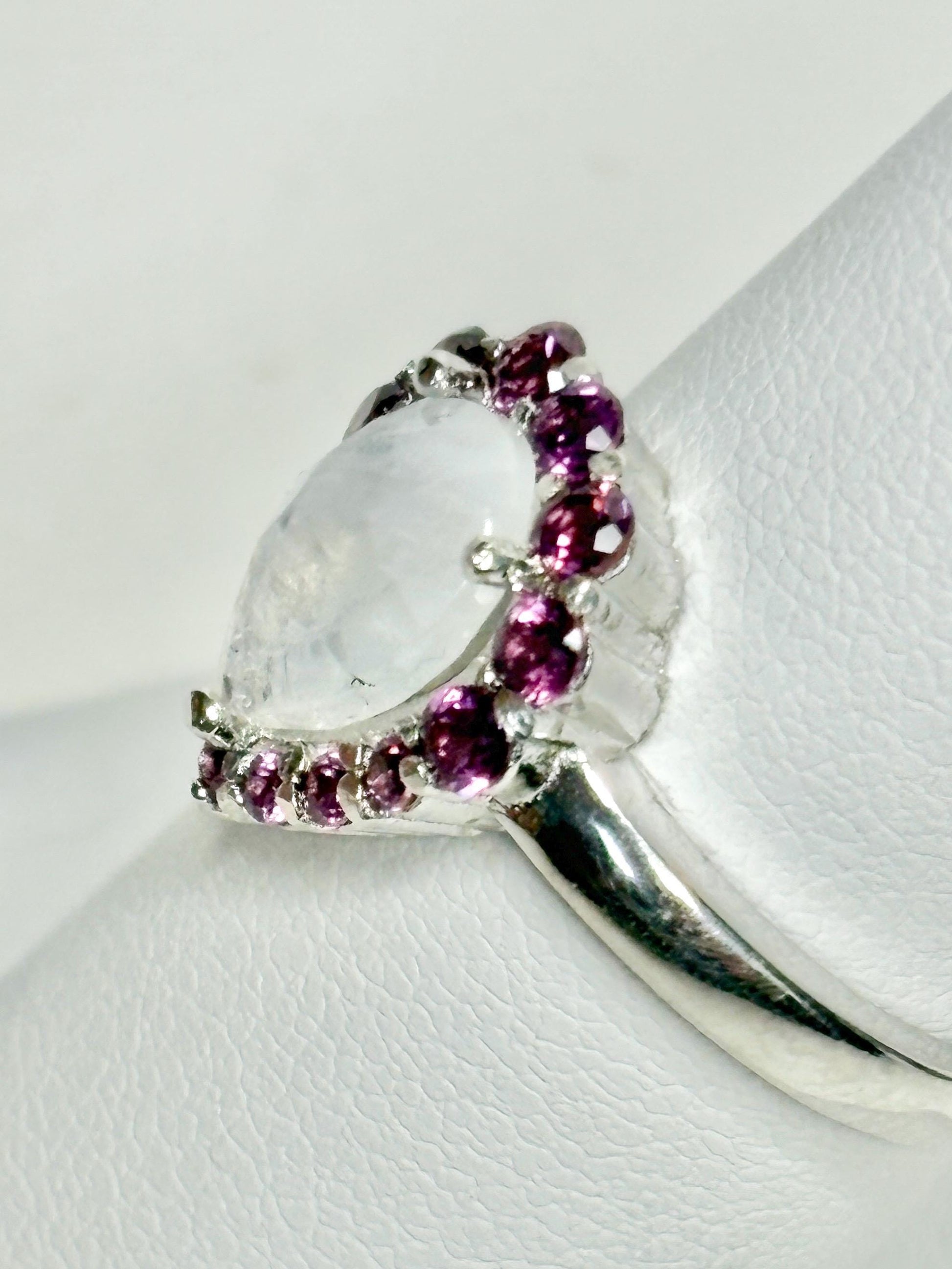 Sterling silver ring with a pear-shaped rainbow moonstone and a halo of rhodolite garnets.