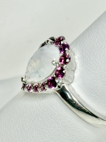 Sterling silver ring with a pear-shaped rainbow moonstone and a halo of rhodolite garnets.