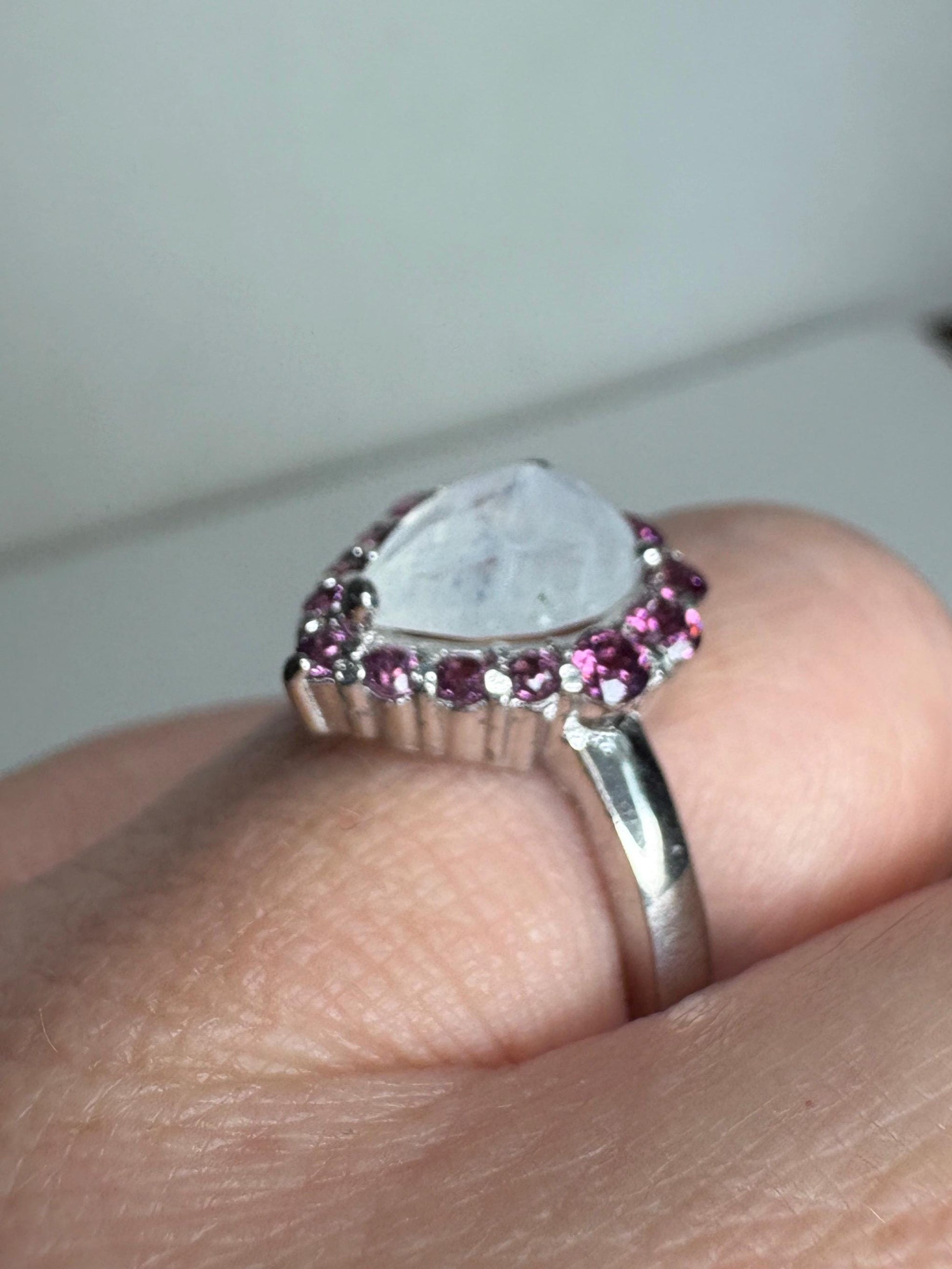 Sterling silver ring with a pear-shaped rainbow moonstone and a halo of rhodolite garnets.