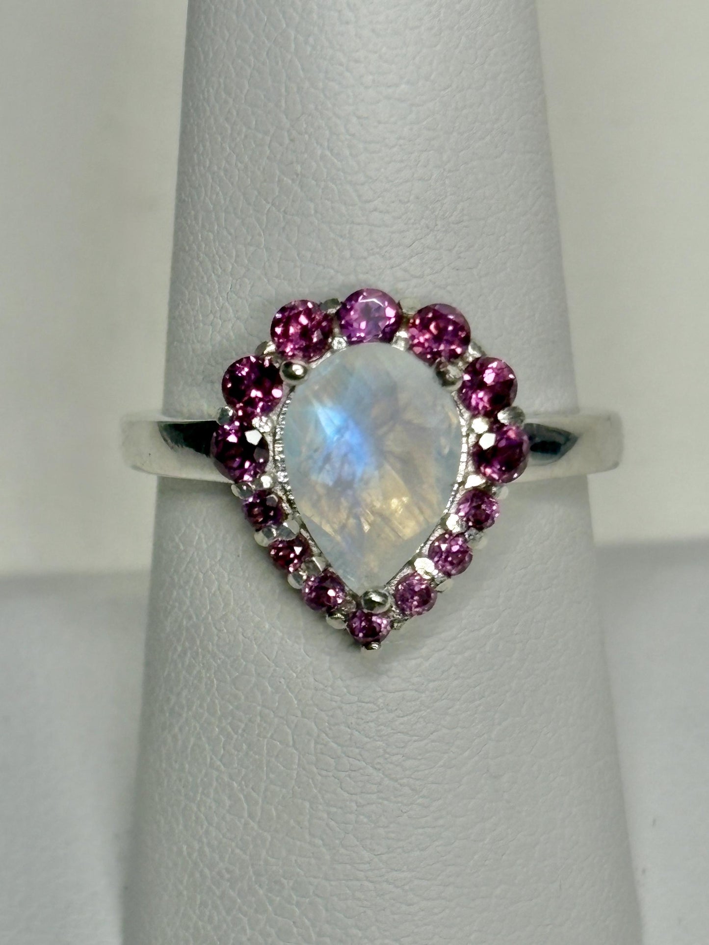 Sterling silver ring with a pear-shaped rainbow moonstone and a halo of rhodolite garnets.