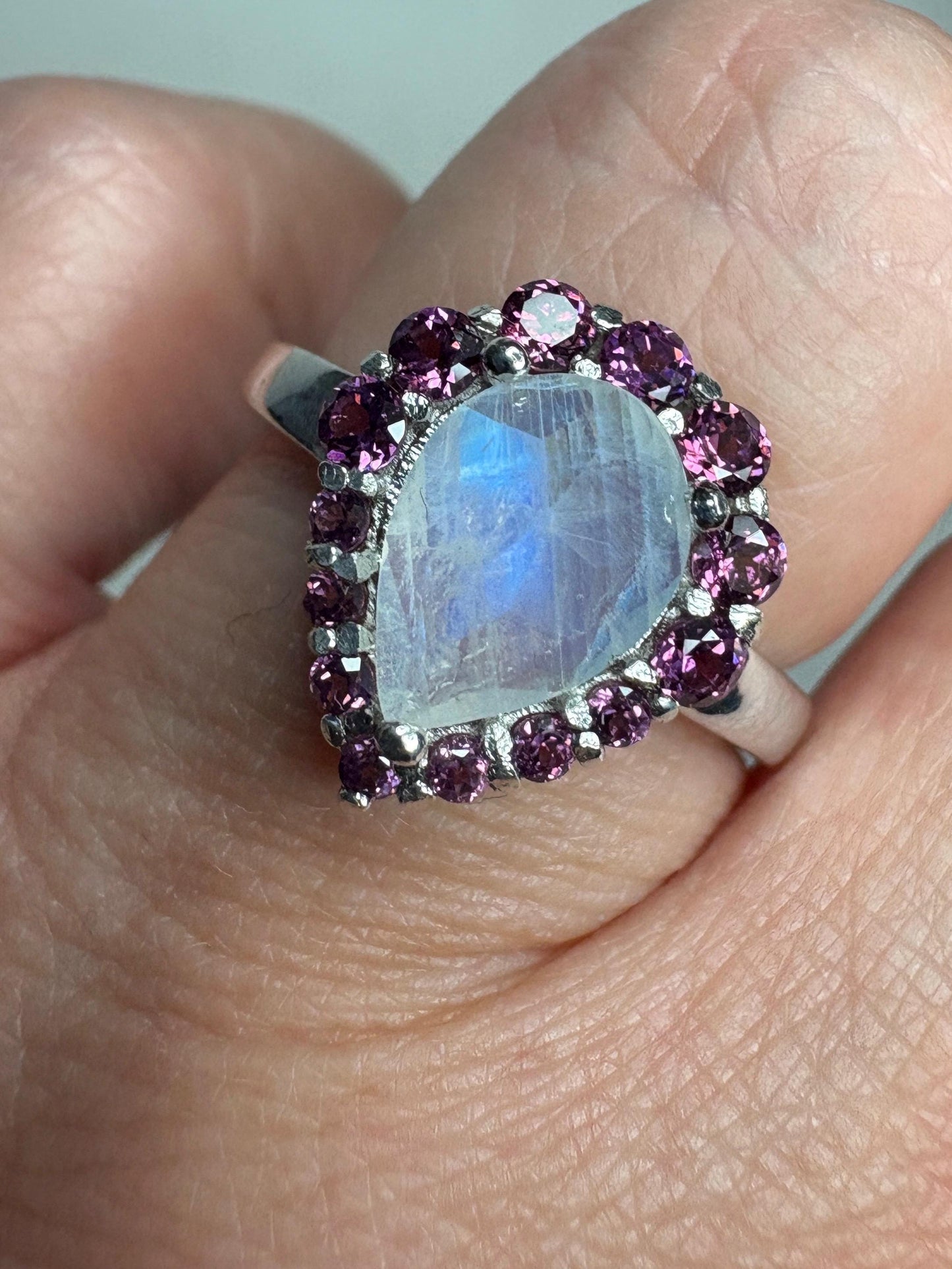 Sterling silver ring with a pear-shaped rainbow moonstone and rhodolite garnet halo.