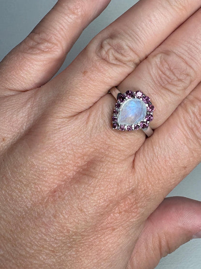 Sterling silver ring with a pear-shaped rainbow moonstone surrounded by rhodolite garnets.