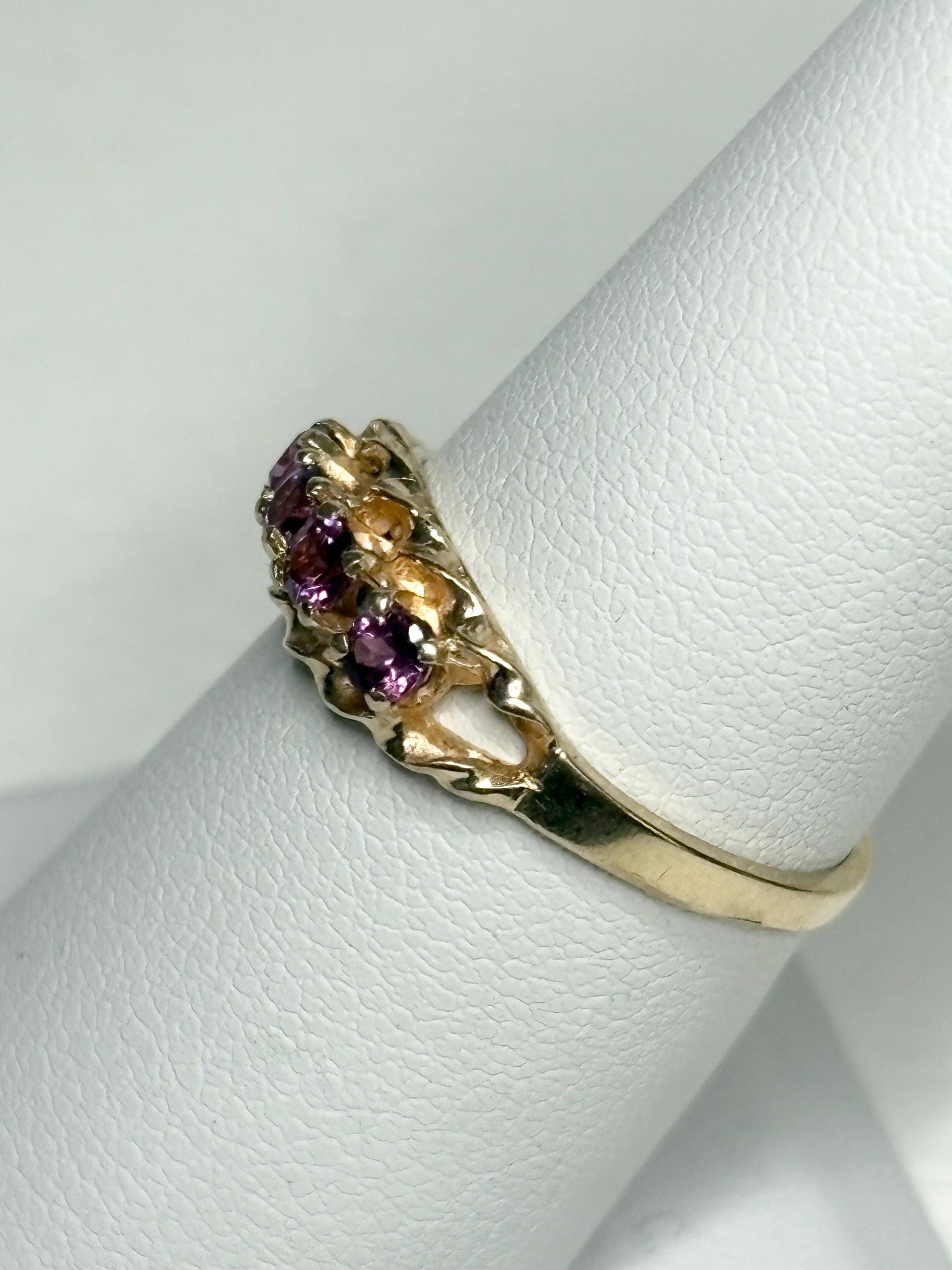 A 10k gold ring with four rhodolite garnets on a rope band.