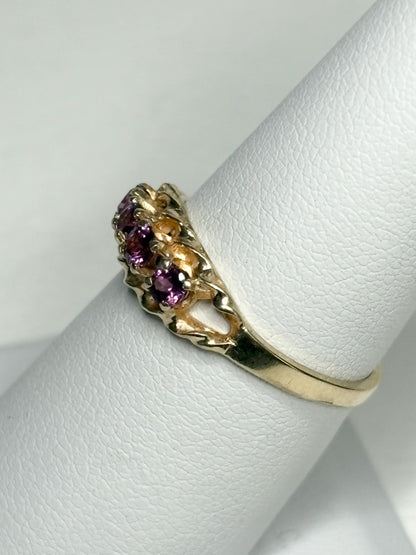 A 10k gold ring with four rhodolite garnets on a rope band.