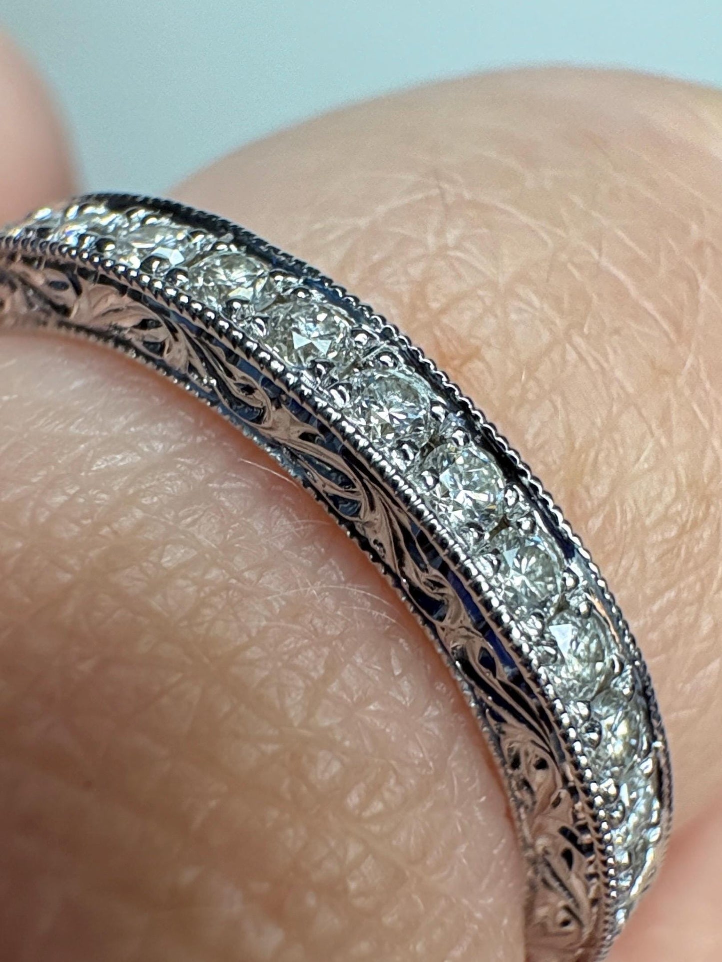 A white gold band ring with diamonds and intricate detailing.