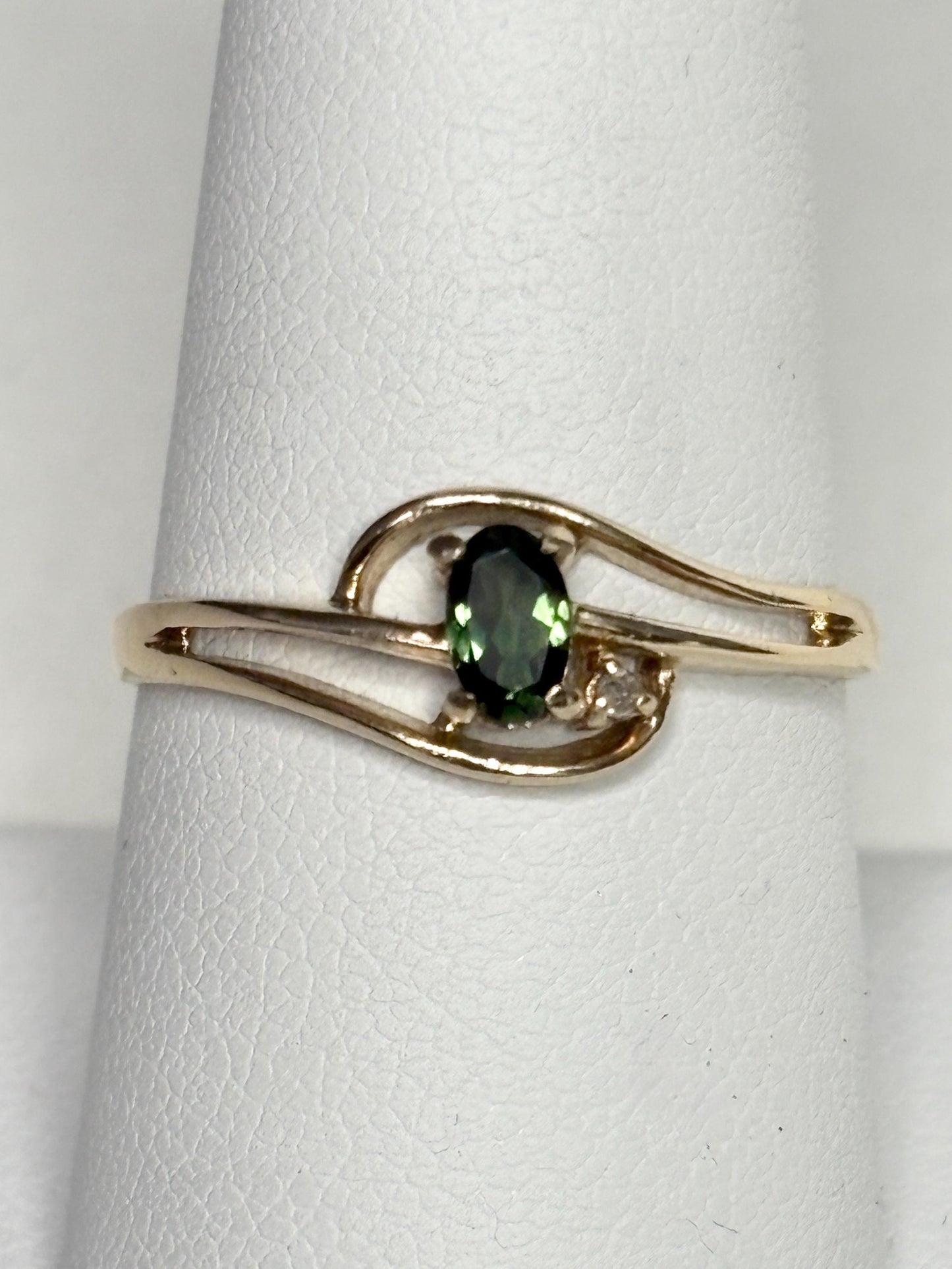10k yellow gold ring with an oval green tourmaline and a diamond accent.