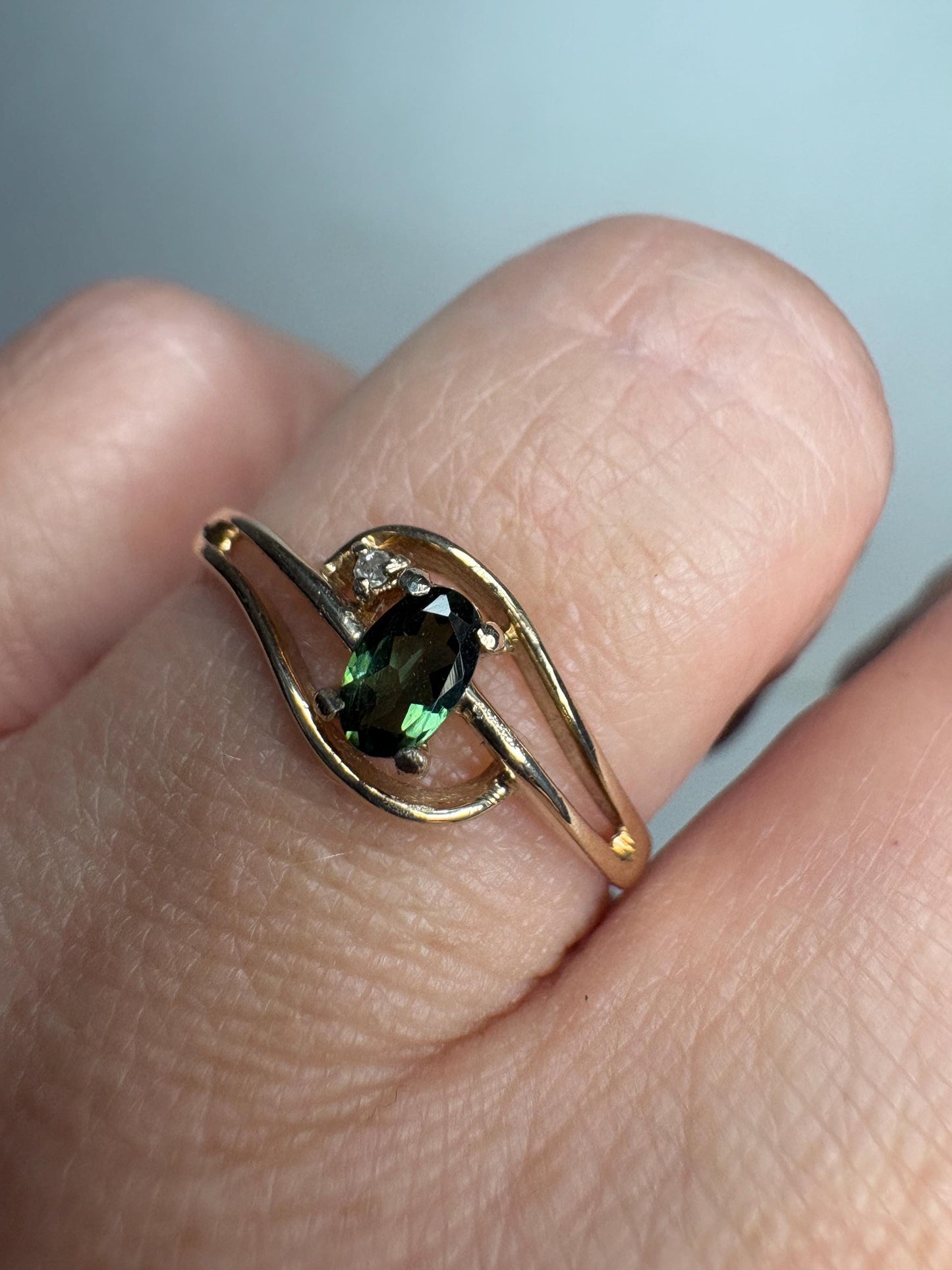 A 10k gold ring with an oval green tourmaline and a small diamond accent.