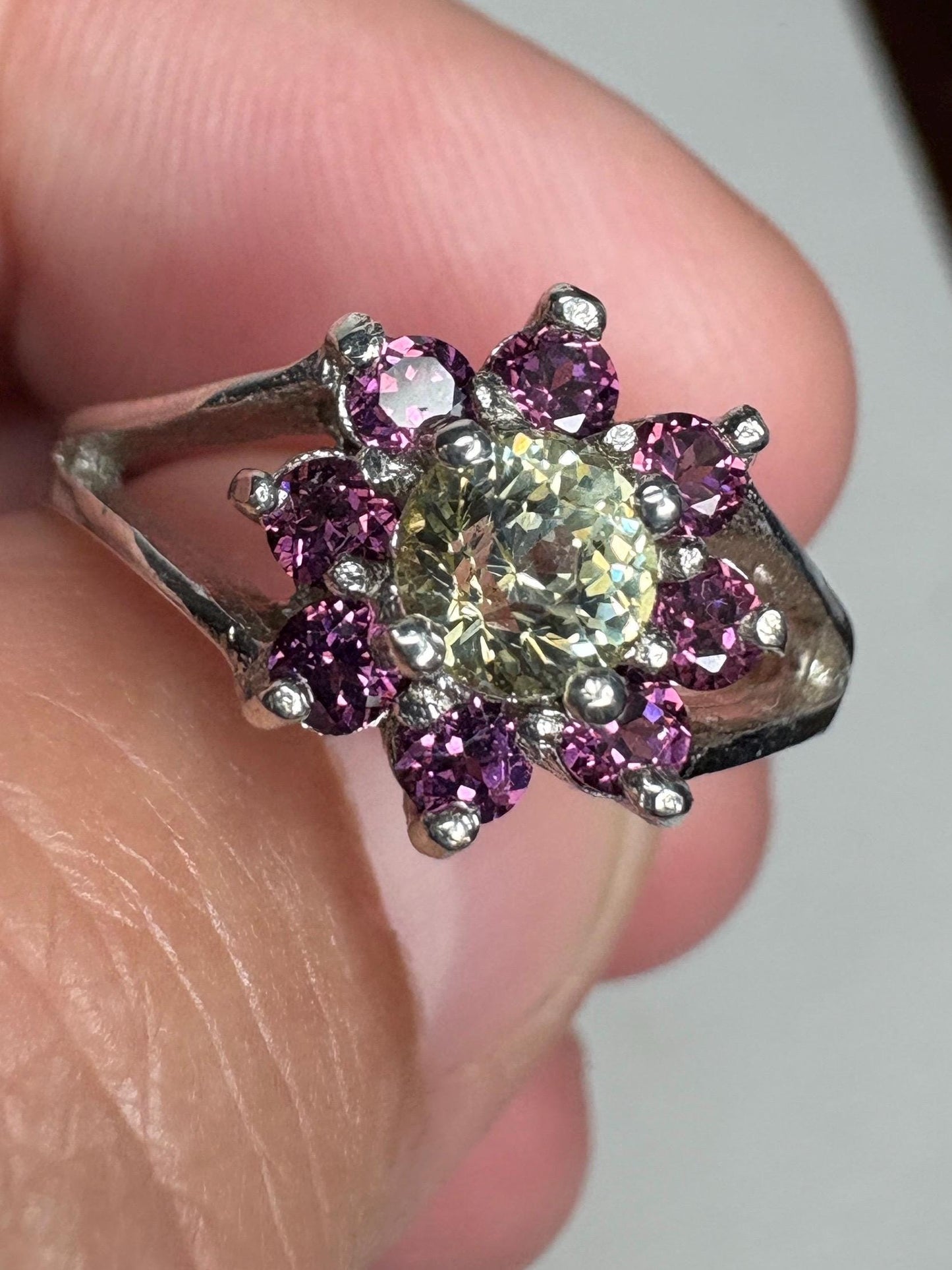 Sterling silver ring with a central light green garnet surrounded by purple rhodolite garnets.