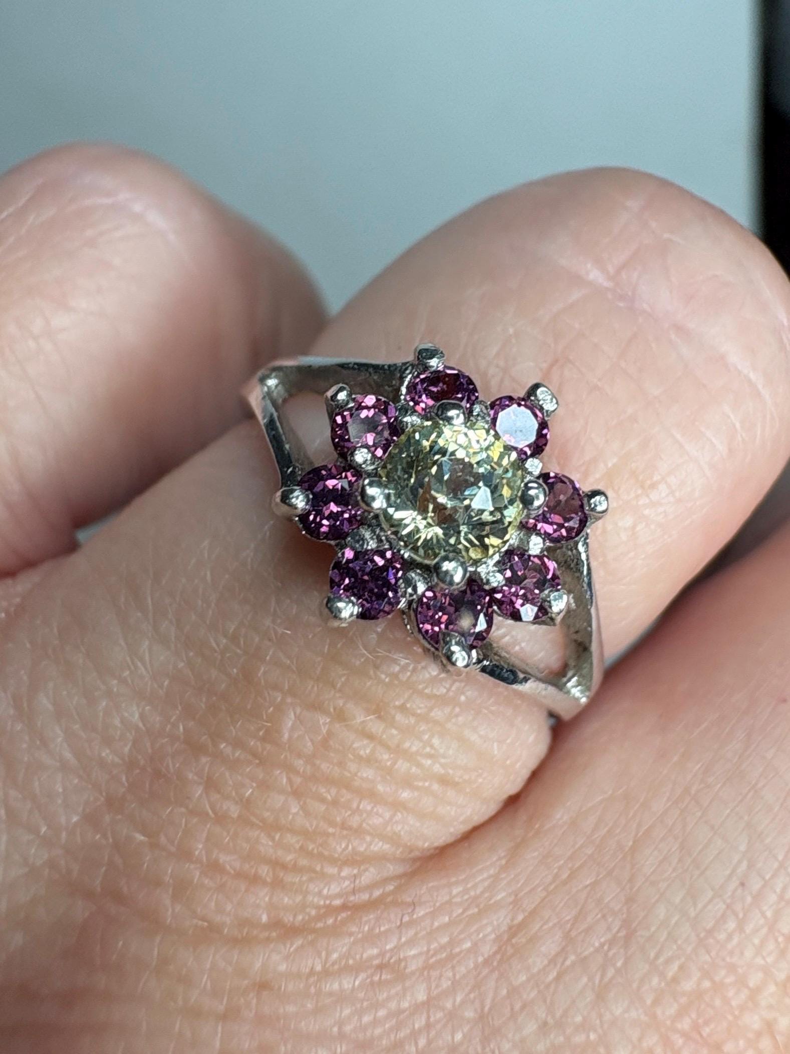 Sterling silver ring with a central Mali garnet surrounded by rhodolite garnets in a daisy design.
