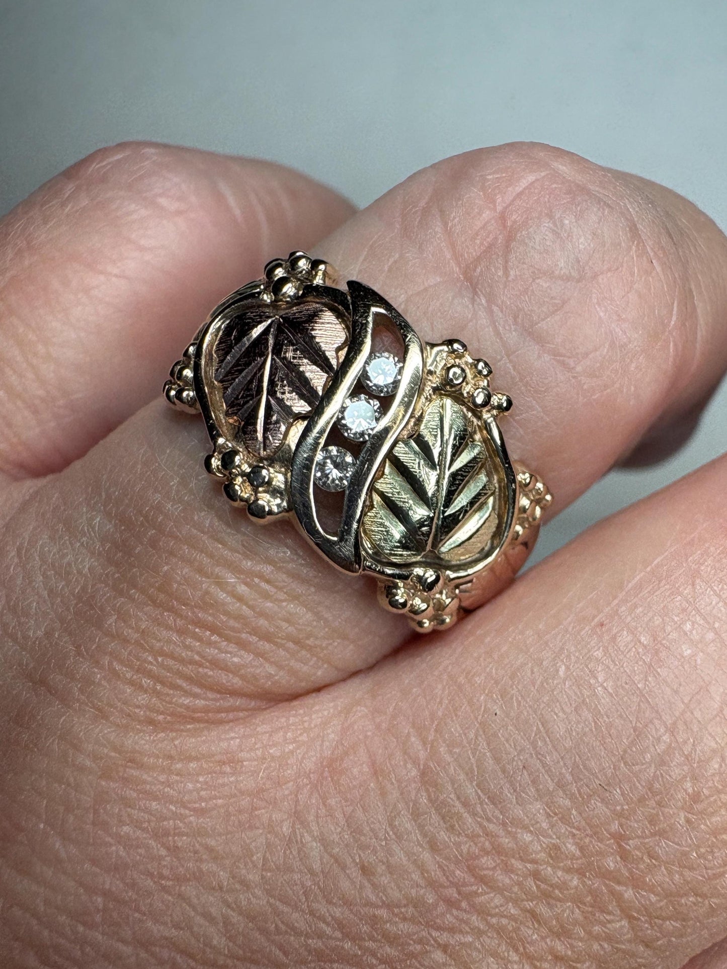 Black Hills Gold ring with three diamonds in tri-color 10k gold.