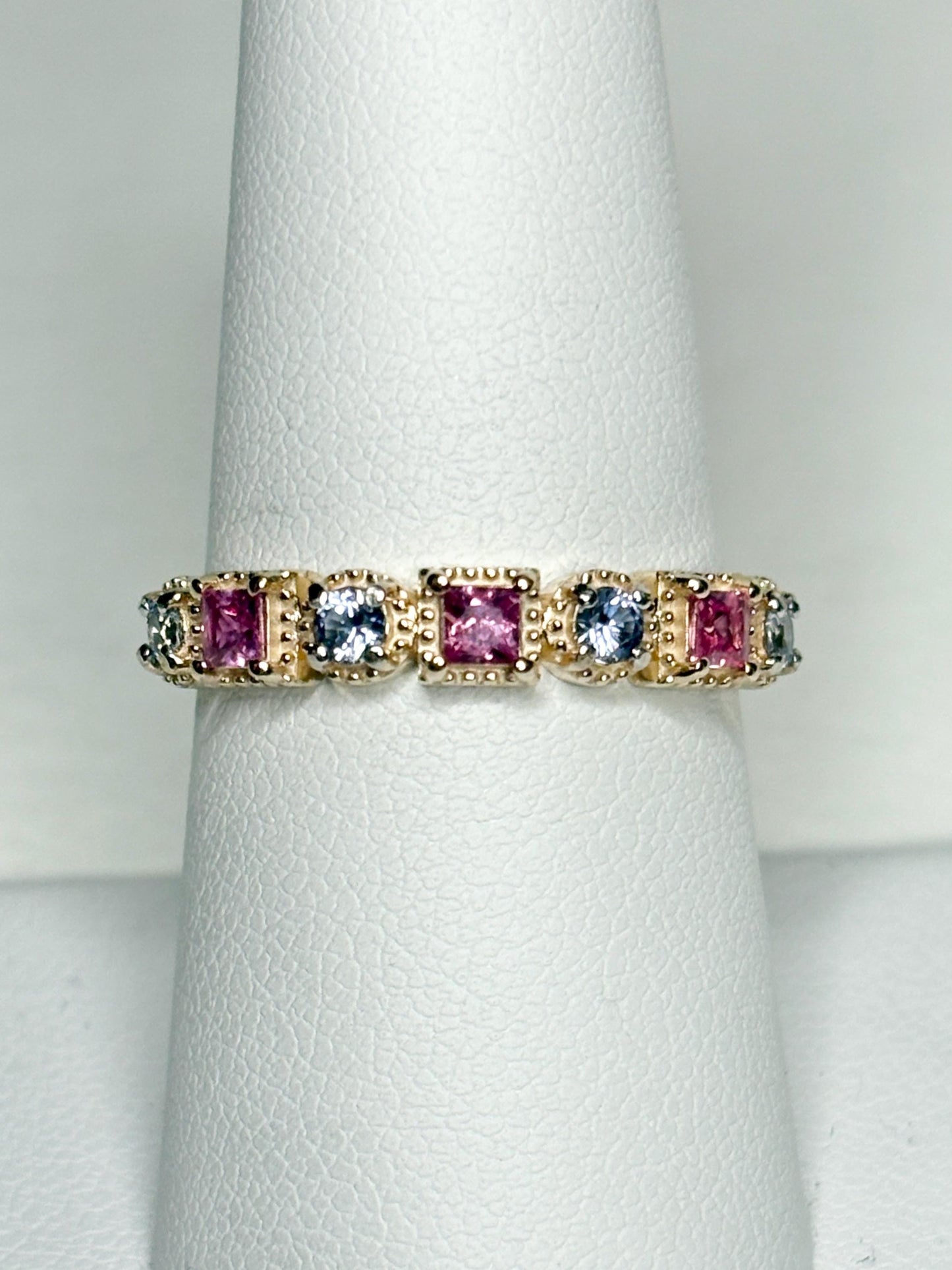 A 9k gold band ring with pink and light violetish blue square sapphires.