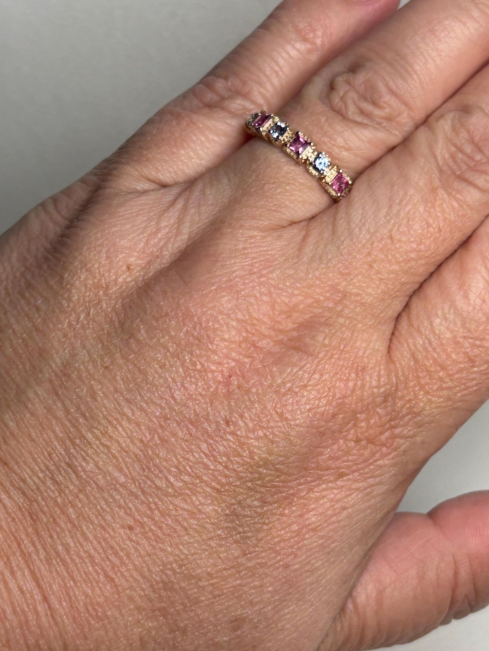 A 9k gold band ring with pink and violetish-blue sapphires.