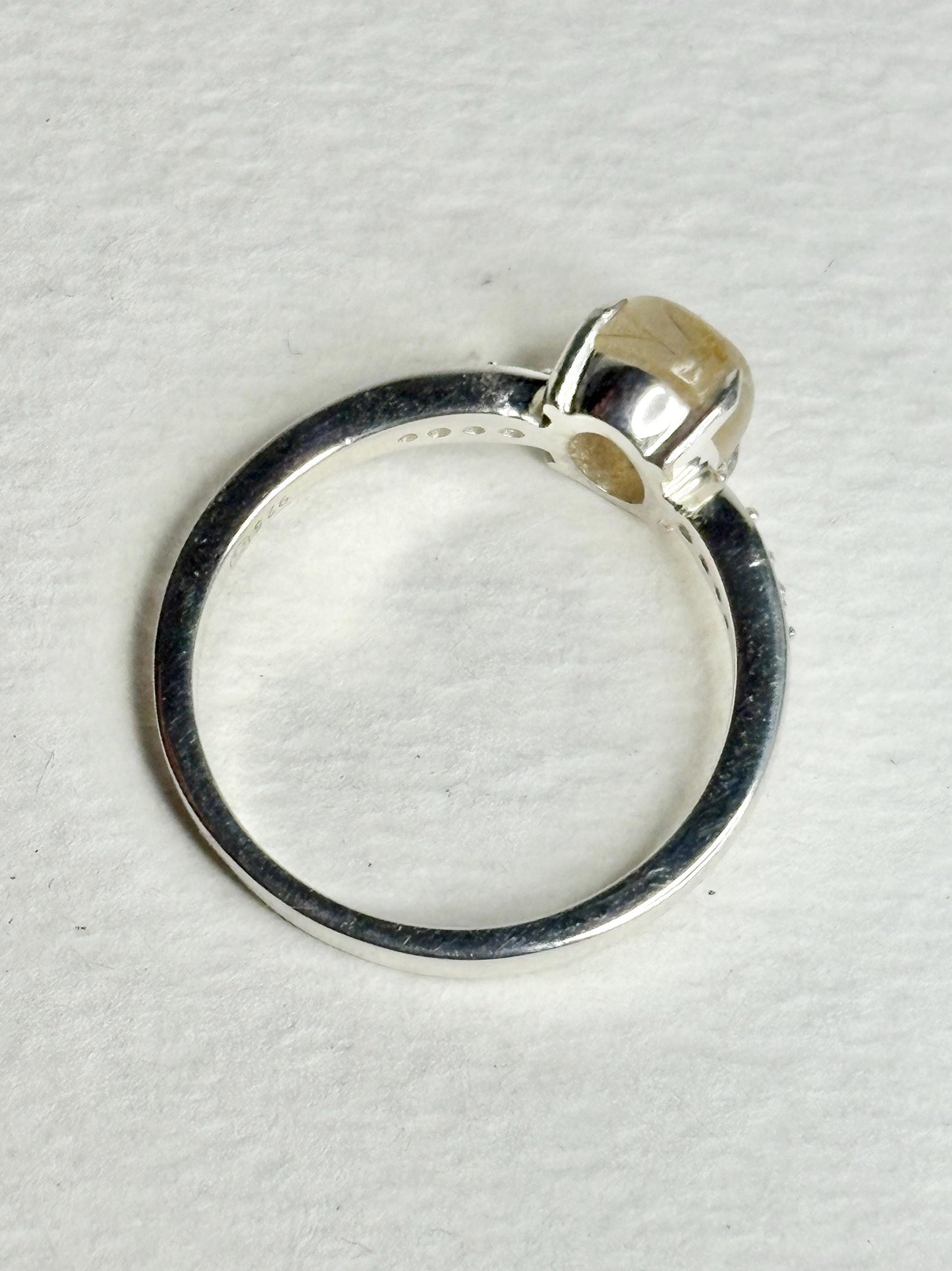 Sterling silver ring with a rutilated quartz cabochon and zircon accents.