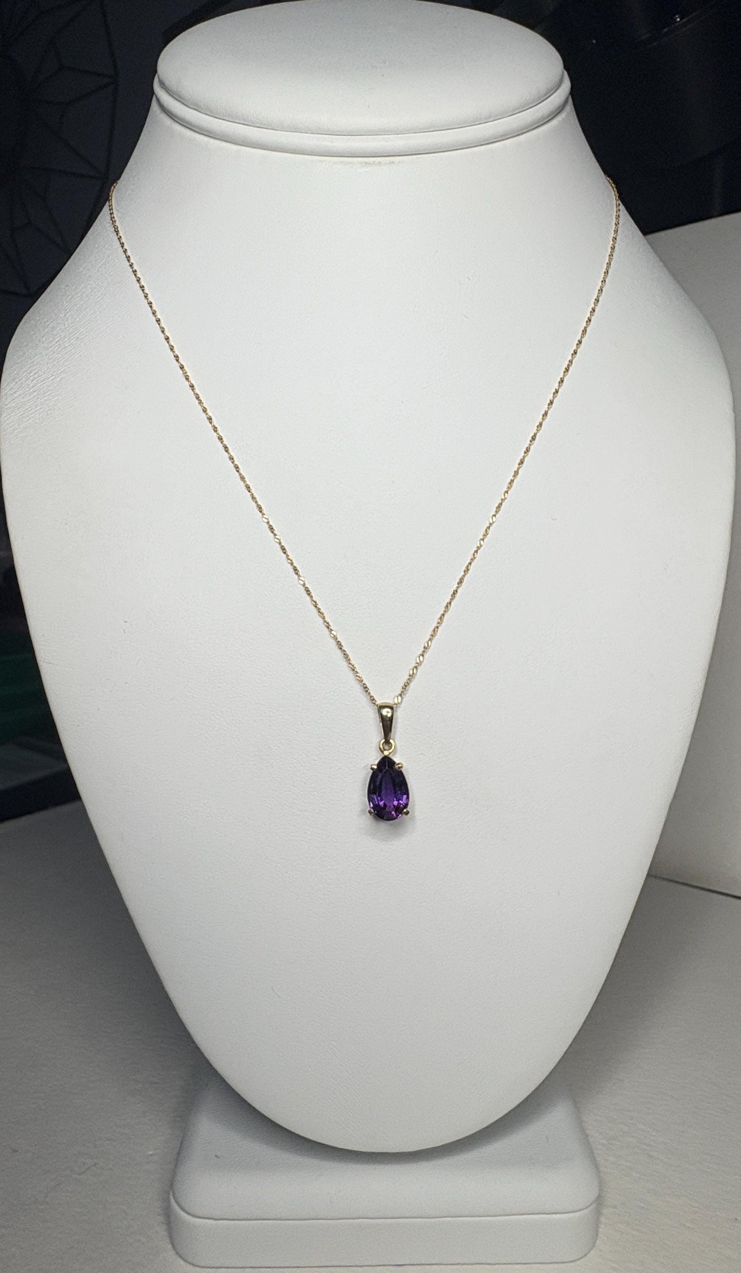 A 14k gold necklace with a pear-shaped amethyst pendant.