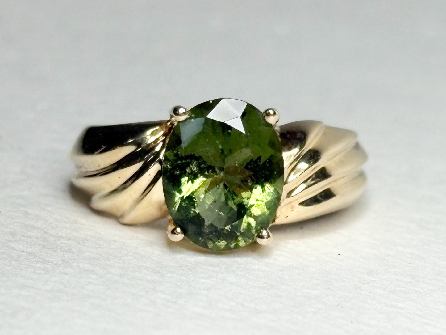 Oval faceted moldavite ring in solid 14k gold.
