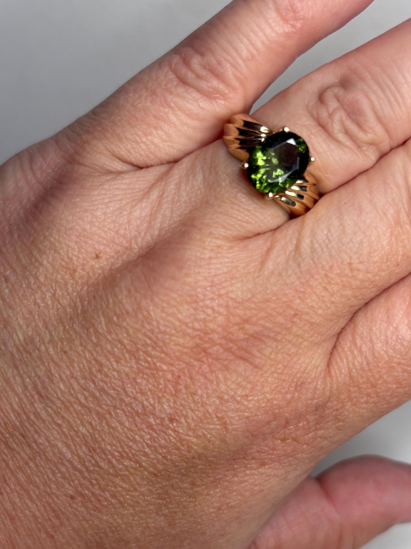 14k gold ring with an oval faceted green moldavite gemstone.