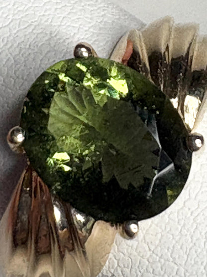 A size 7 solid 14k gold ring featuring an oval, faceted moldavite gemstone.
