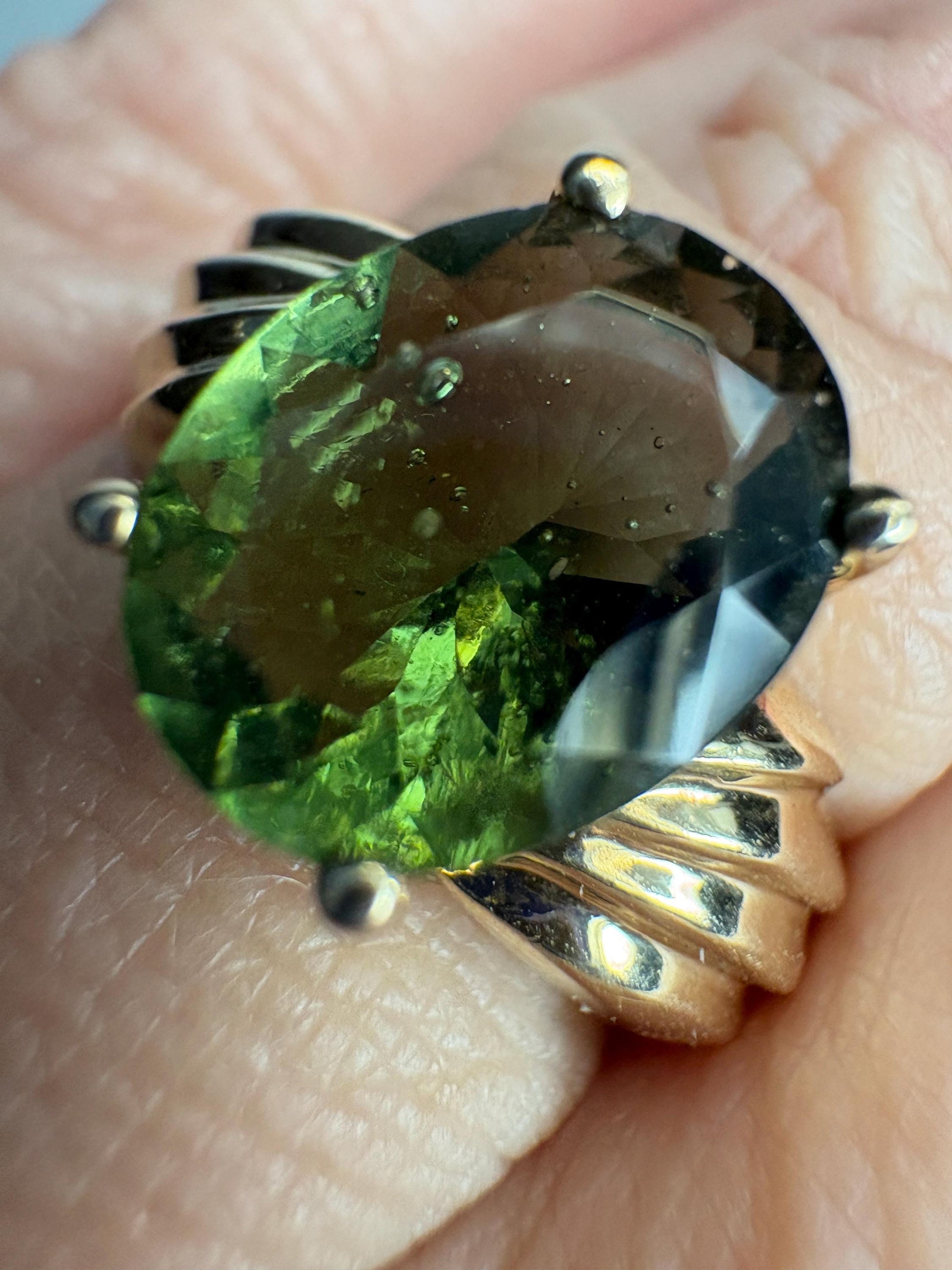 A size 7 solid 14k gold ring featuring an oval, faceted moldavite gemstone.