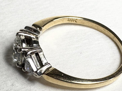 An 18k gold ring with three diamonds, including a central round diamond.