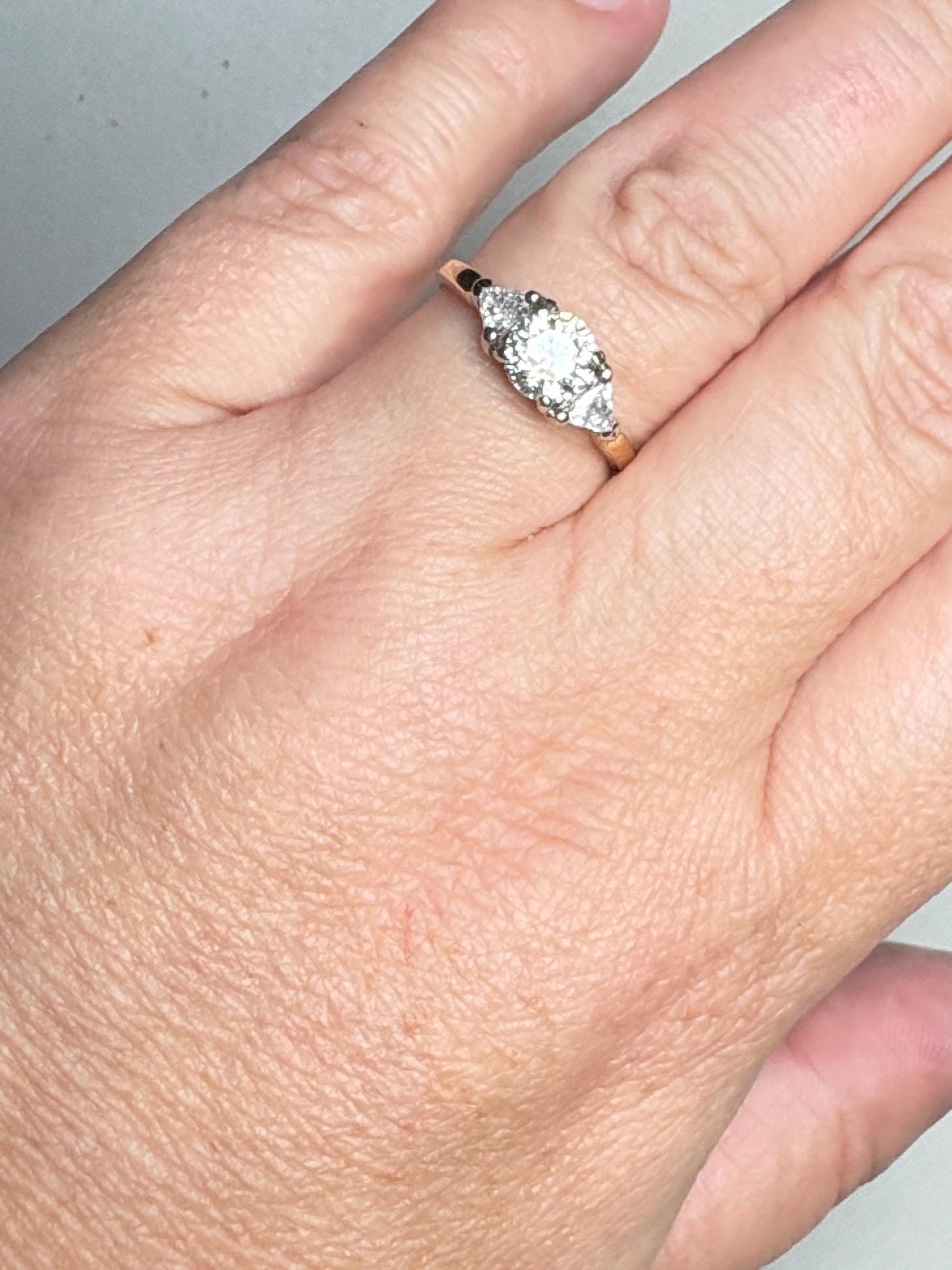 A round diamond engagement ring with trillion side stones in 18k gold.