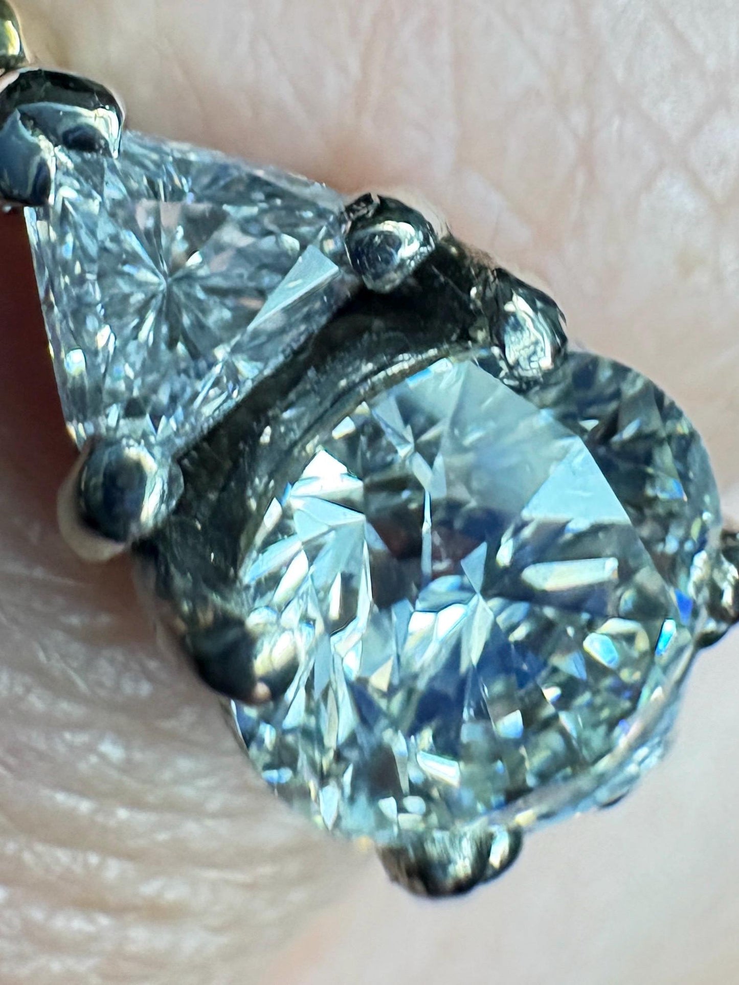 Engagement ring with a round diamond and two trillion diamonds in 18k gold.