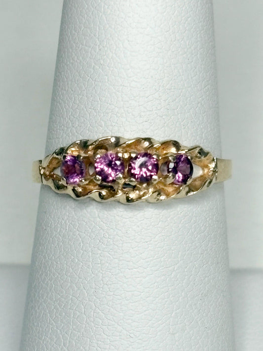 A 10k gold ring with five rhodolite garnets and a rope band.