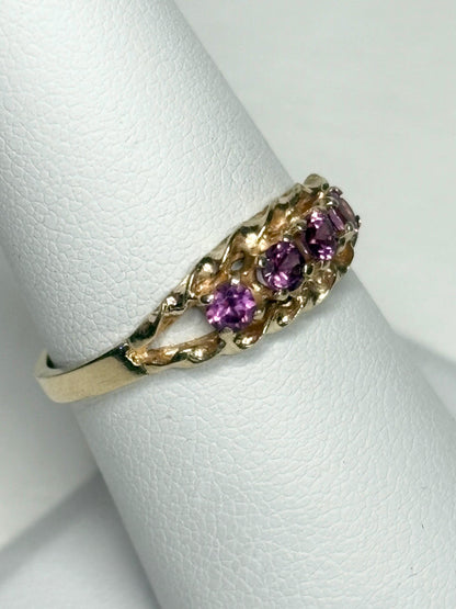 A 10k gold ring with four rhodolite garnets set in a rope band.