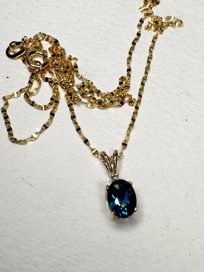 14k gold necklace with an oval London blue topaz pendant and diamond accent.