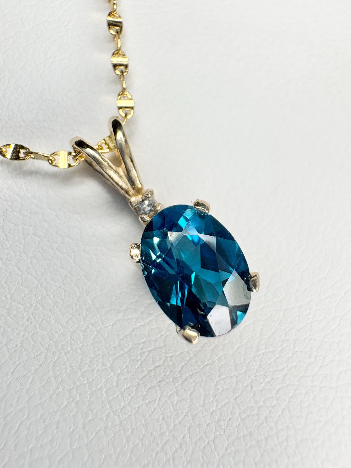 Oval London blue topaz pendant necklace with diamond accent in 14k gold.