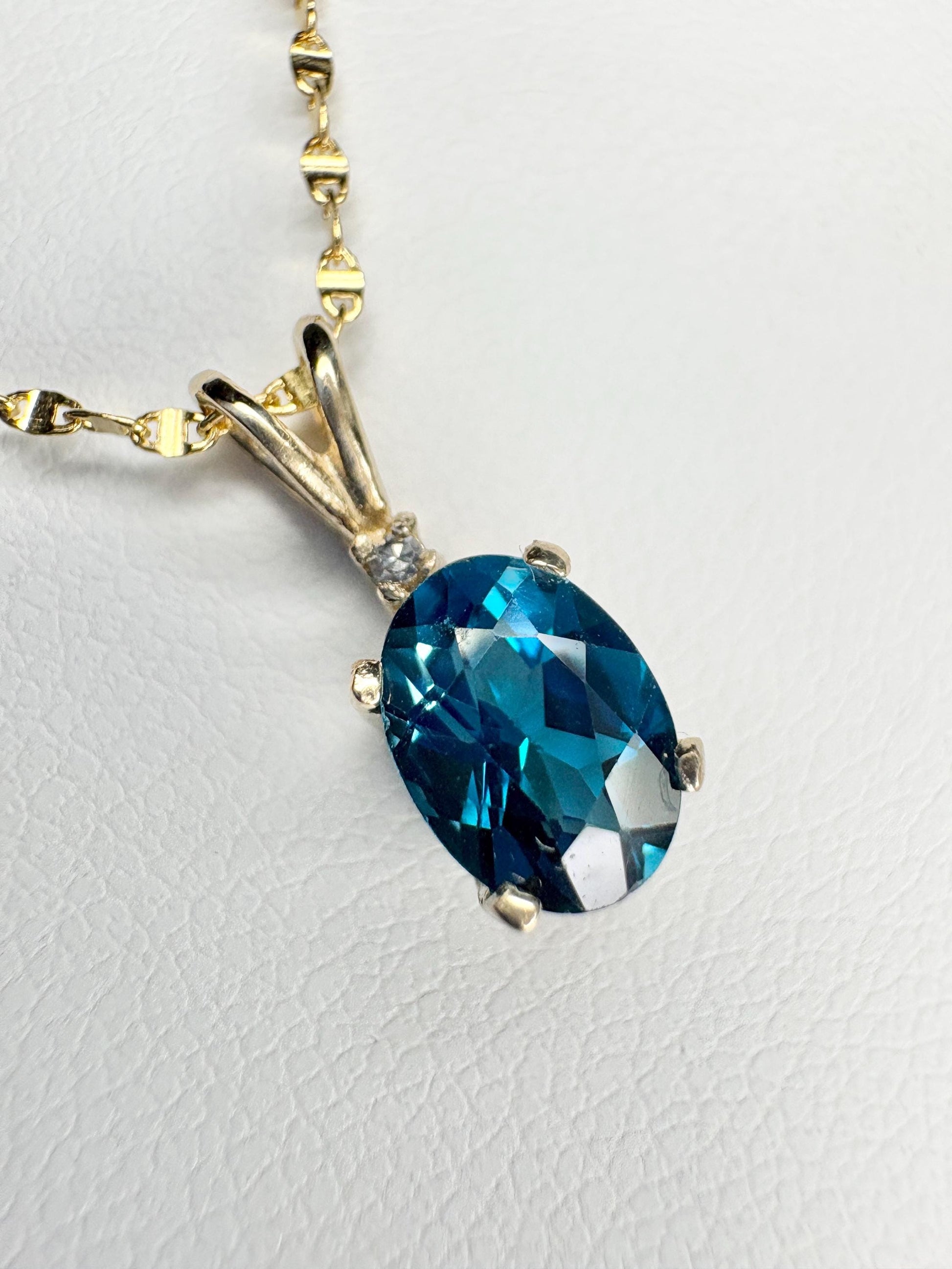 Oval London blue topaz pendant necklace with diamond accent in 14k gold.