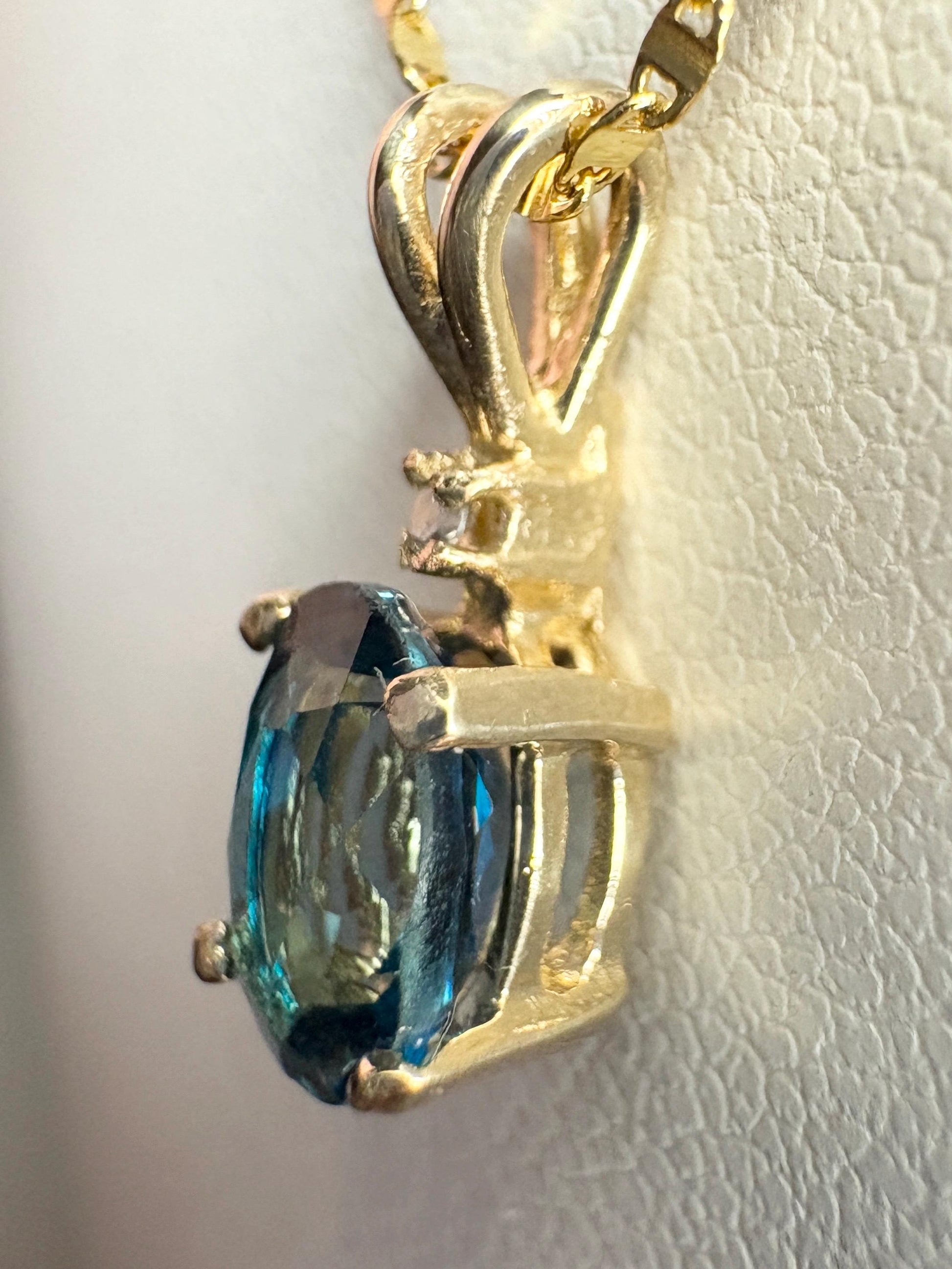 Oval London blue topaz pendant necklace with diamond accent in 14k gold.