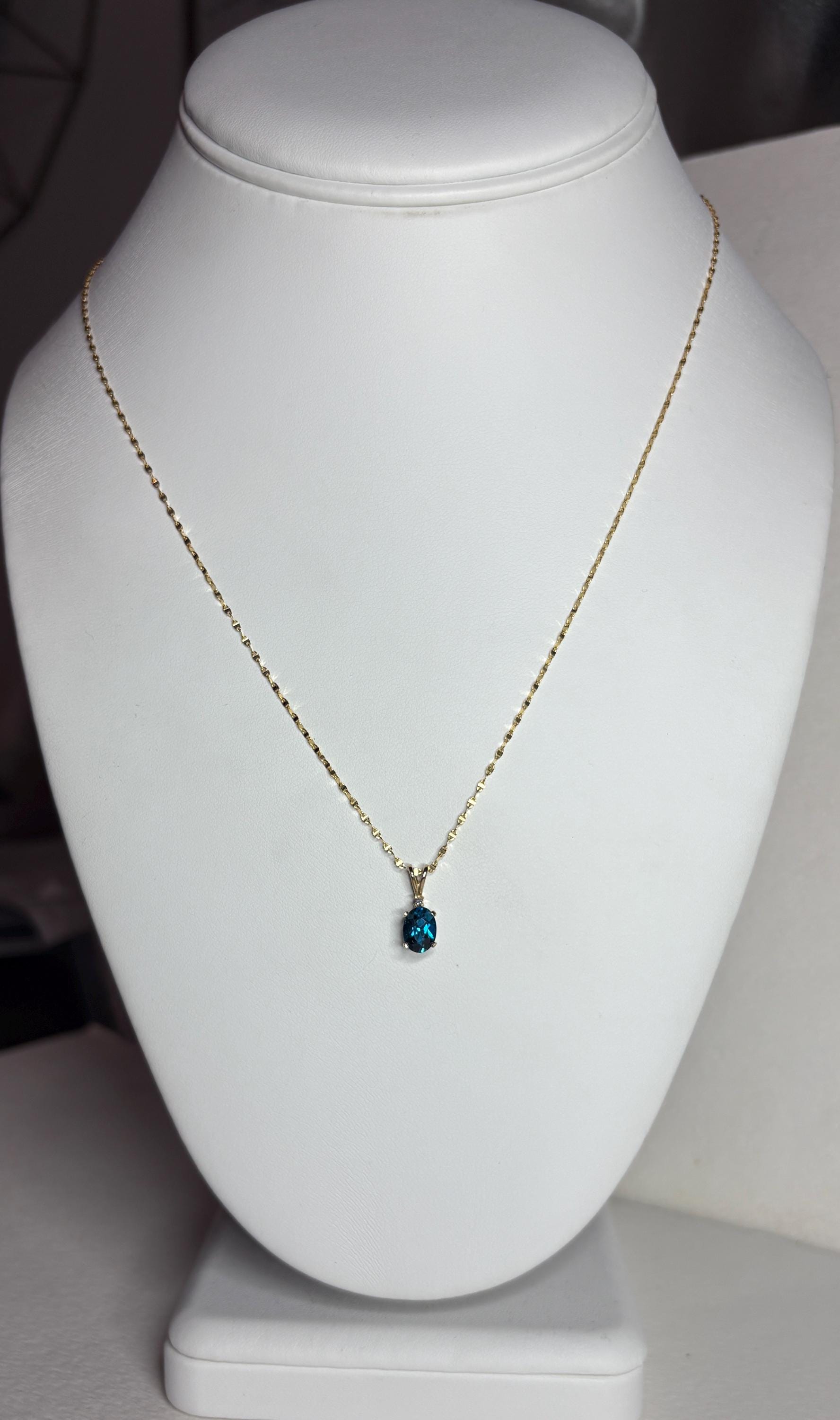 14k gold necklace with an oval London blue topaz pendant and diamond accent.