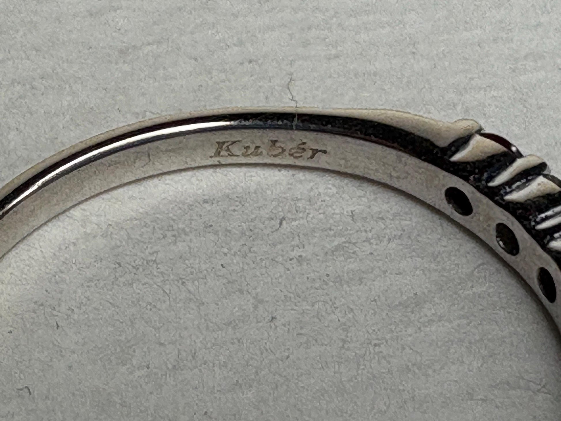 A white gold band ring with the engraving "Kuber".