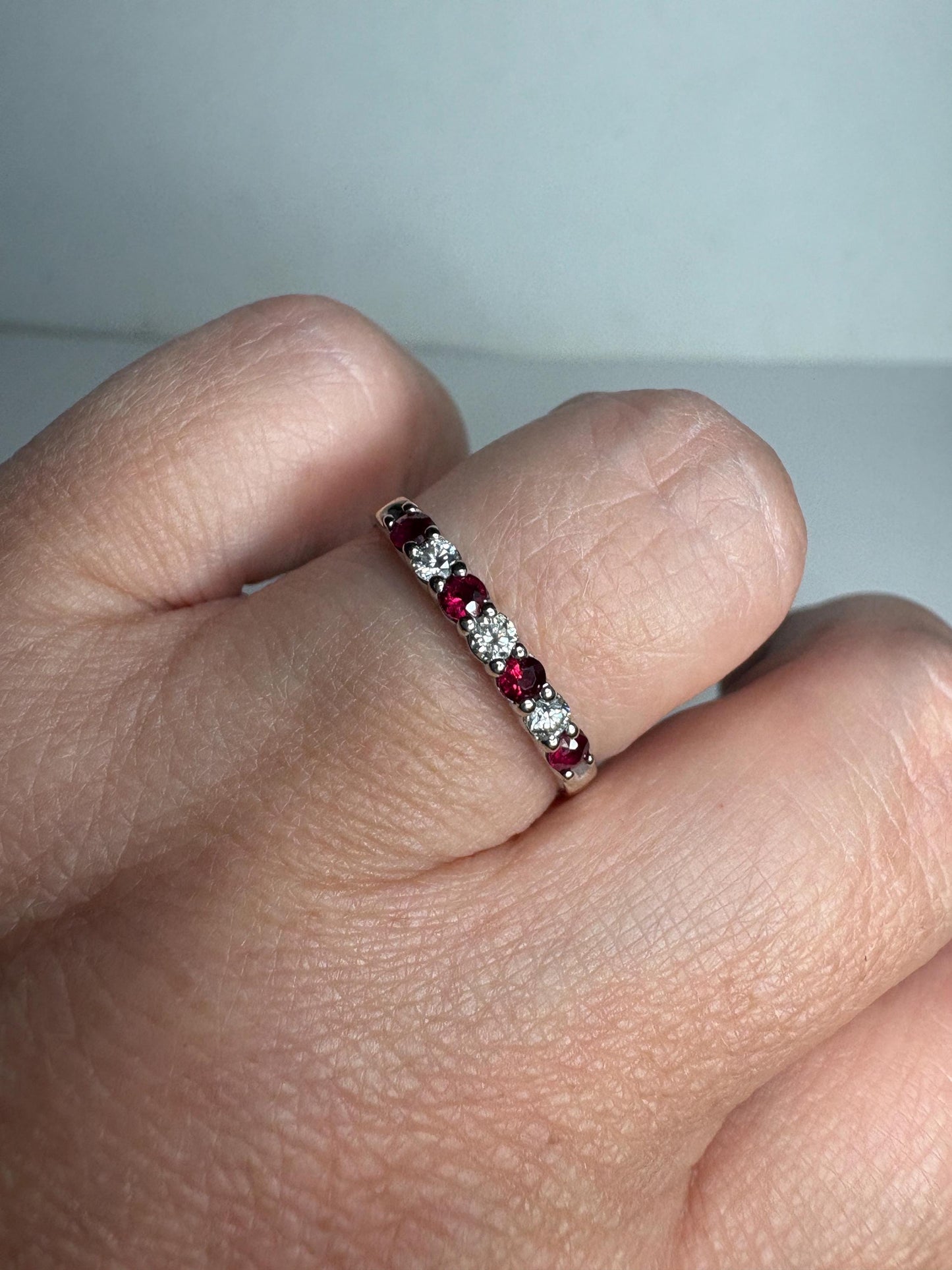 A 14k white gold band ring with alternating rubies and diamonds.