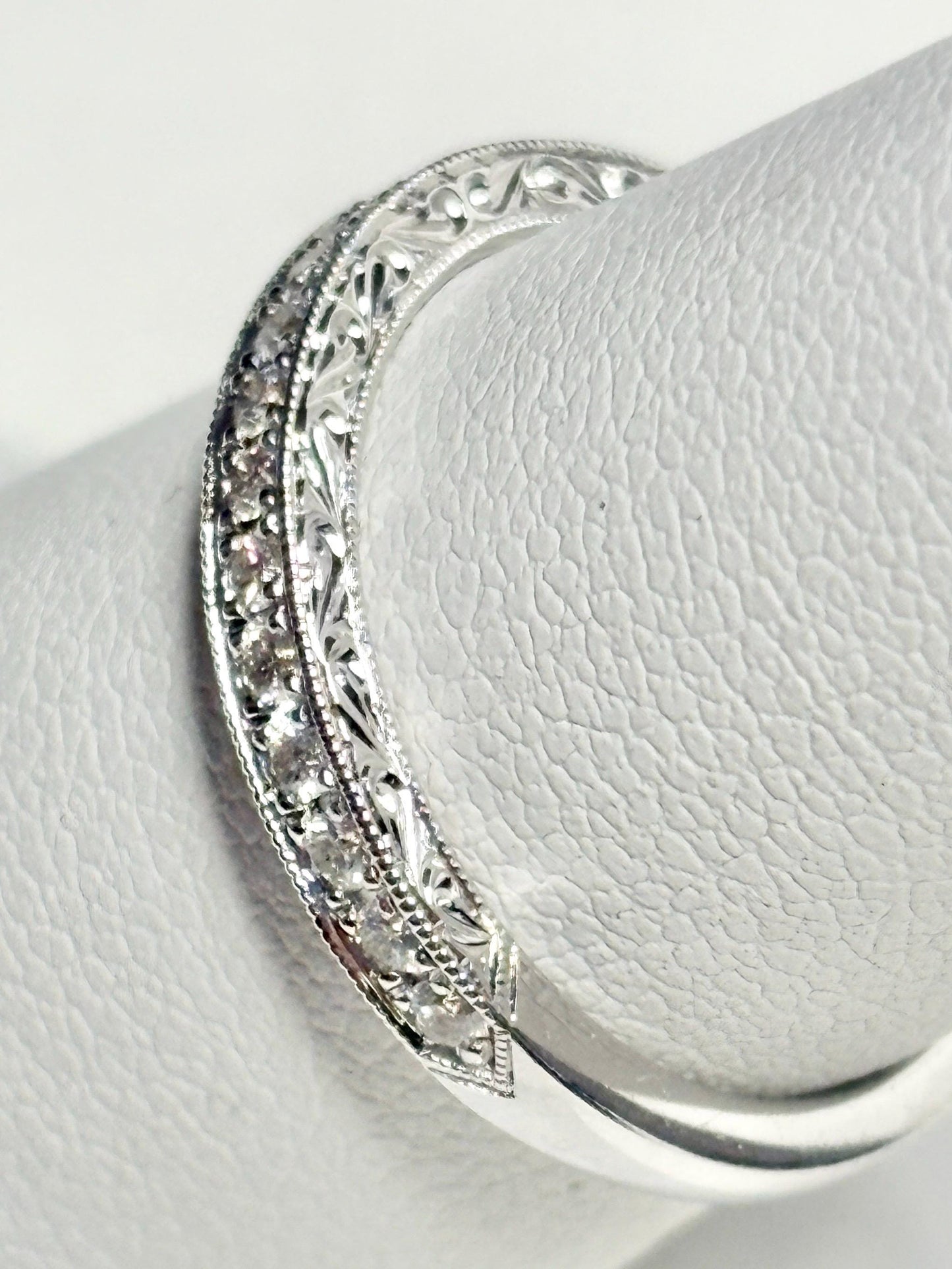 A 14k white gold band with diamonds and intricate detailing.
