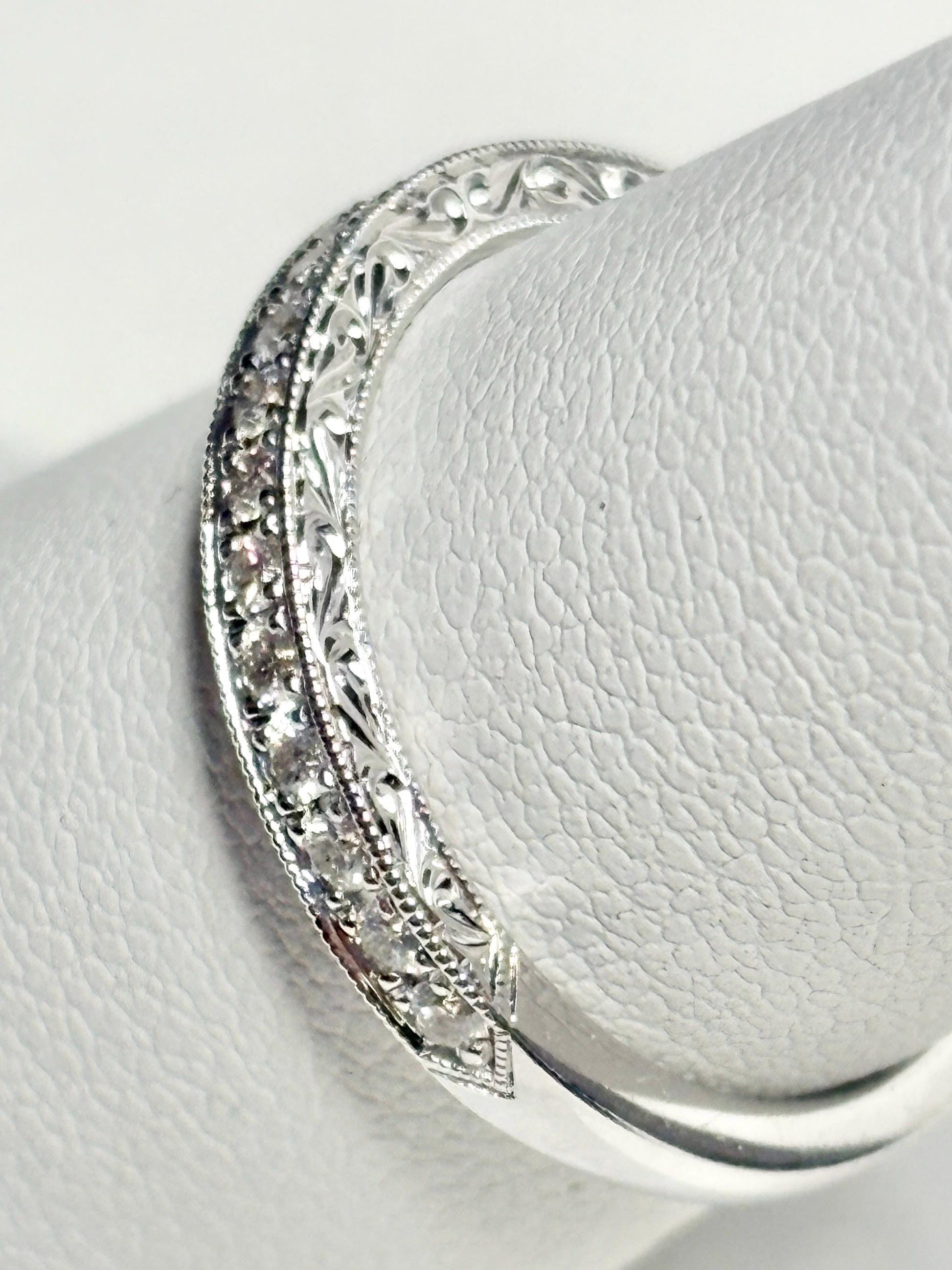 A 14k white gold band with diamonds and intricate detailing.