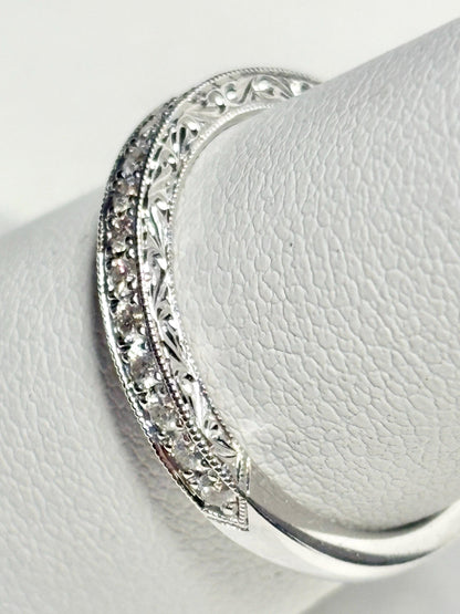A 14k white gold band with diamonds and intricate detailing.