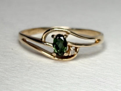 10k gold ring with oval green tourmaline and diamond accent.