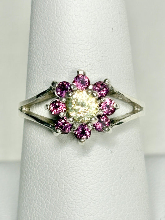 Sterling silver ring with a central yellow garnet surrounded by pink rhodolite garnets in a daisy halo design.