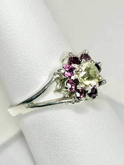 Sterling silver ring with a central light green garnet surrounded by purple rhodolite garnets.