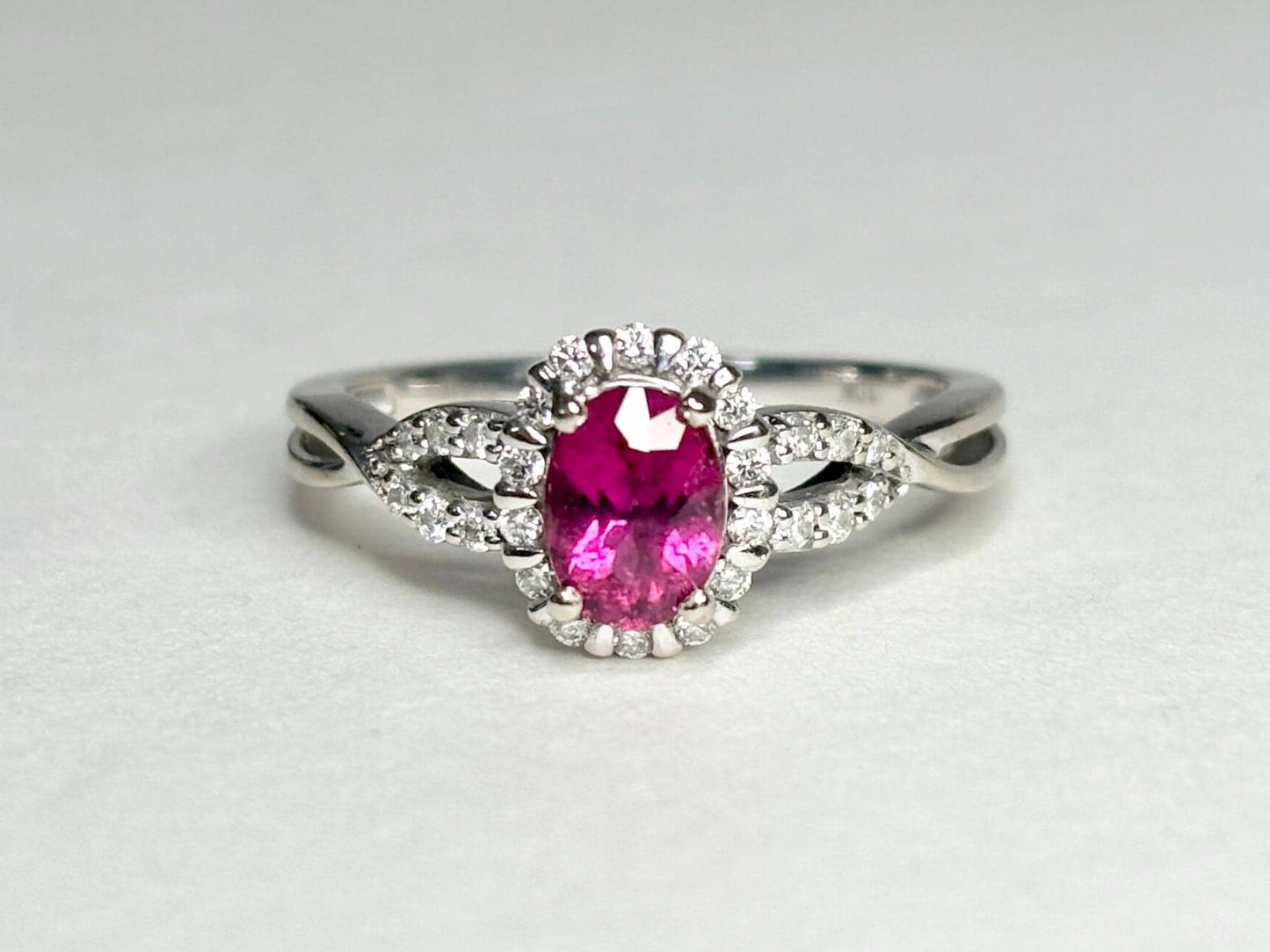 Oval rubellite tourmaline and diamond halo ring in 10k white gold.