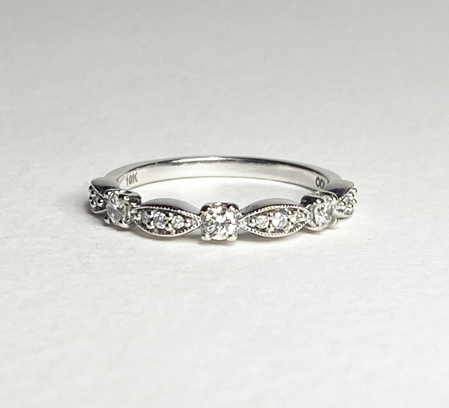 A 10k white gold band ring with small diamonds and milgrain detailing.