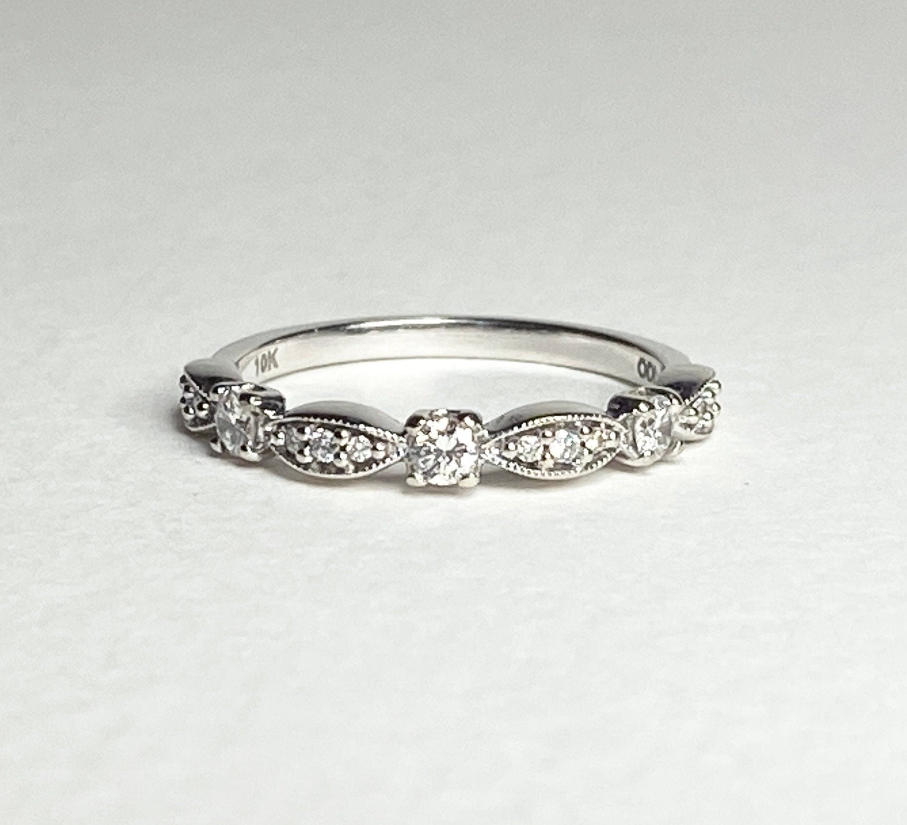 A 10k white gold band ring with small diamonds and milgrain detailing.