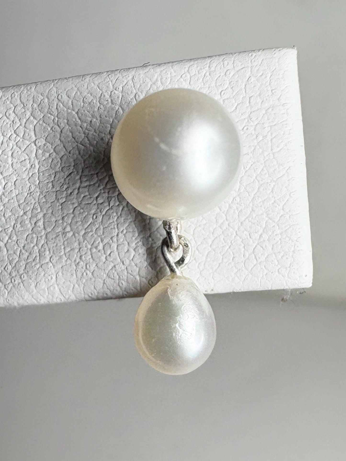 Sterling silver earrings with round freshwater pearls and a dangling teardrop pearl.