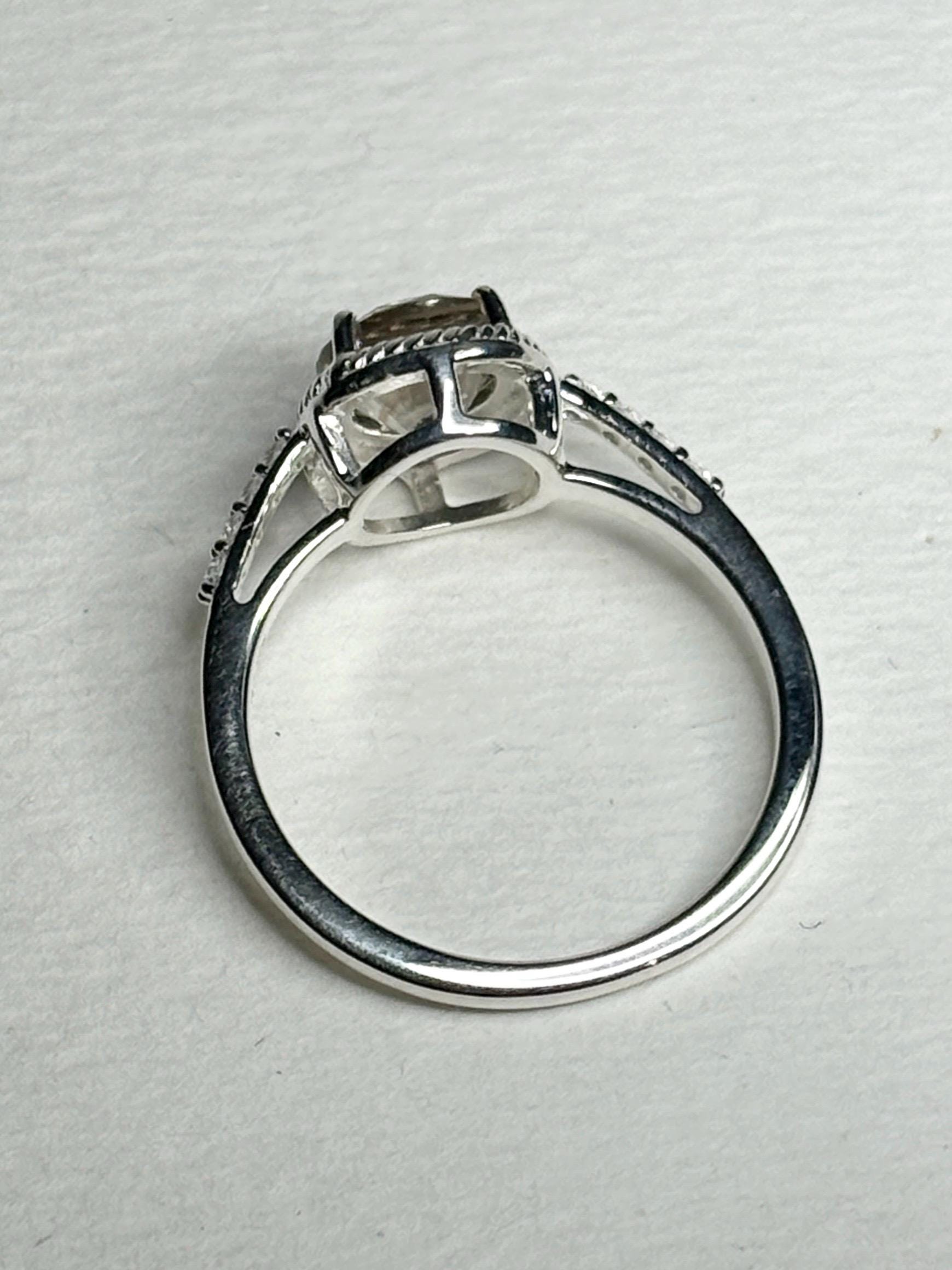 Sterling silver ring with a light peach Oregon sunstone, white topaz accents, and rope design.