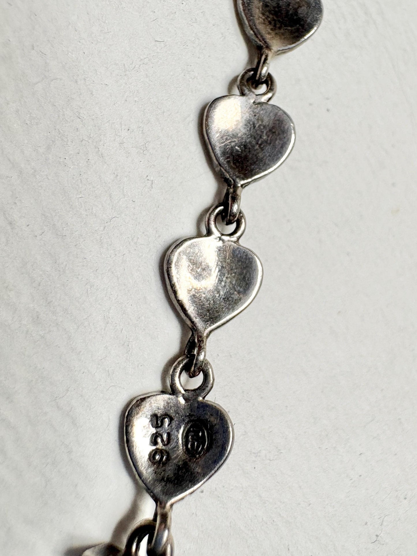 Sterling silver bracelet with heart links and "925" stamp.