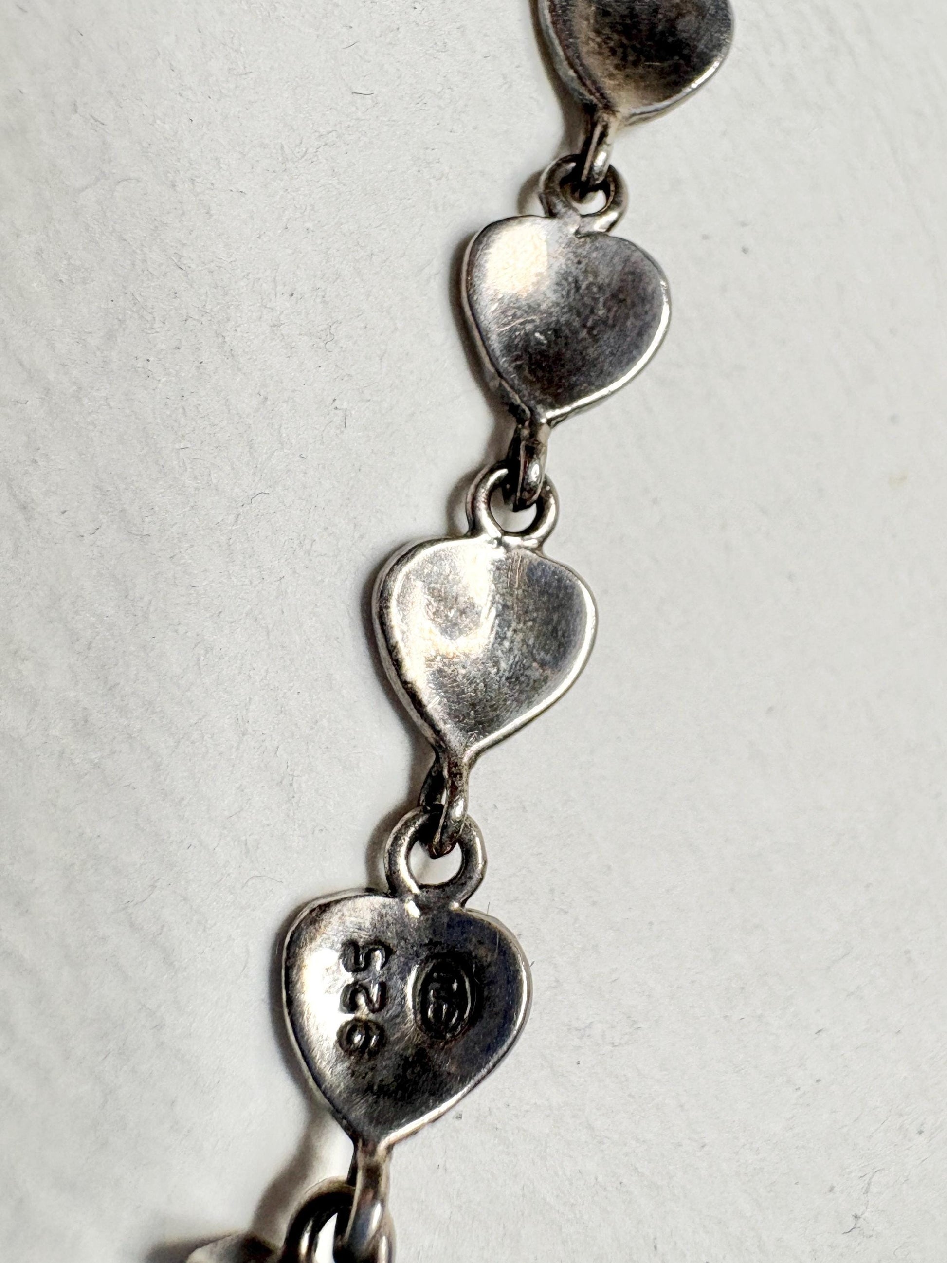 Sterling silver bracelet with heart links and "925" stamp.
