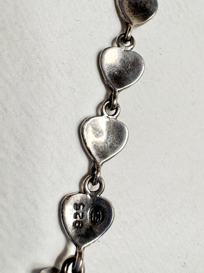 Sterling silver bracelet with heart links and "925" stamp.